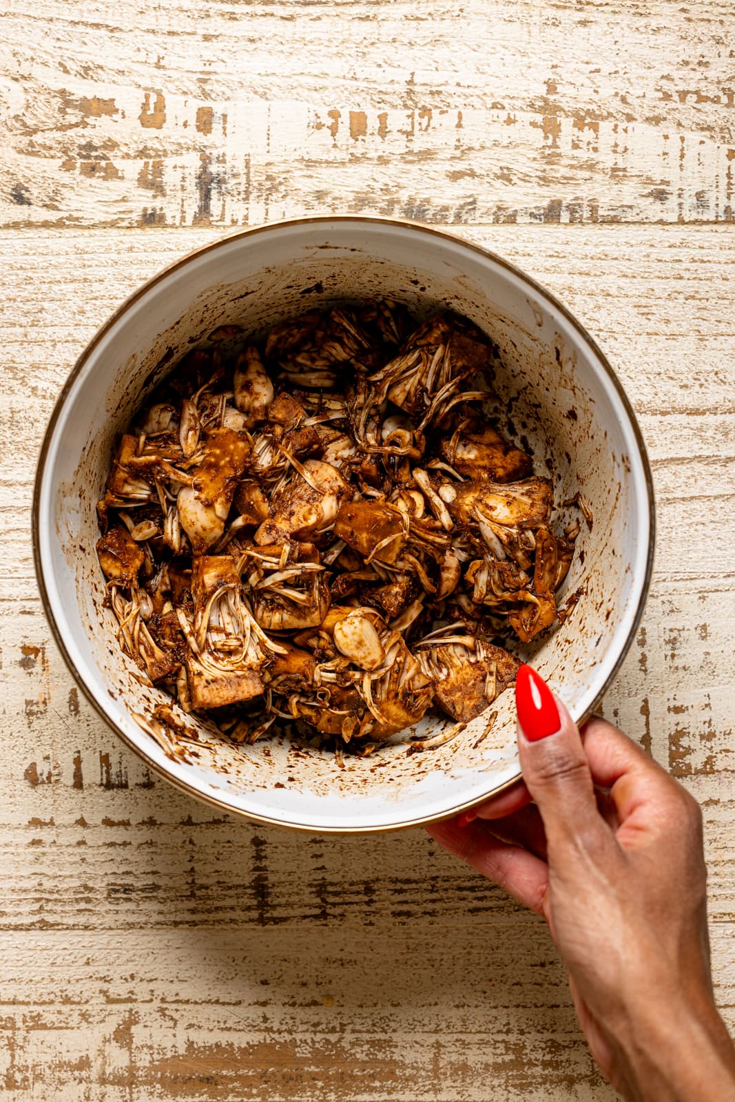 Bowl full of marinated jackfruit being held.