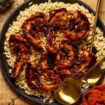 Up close shot of lobster and orzo in a skillet with serving spoons.