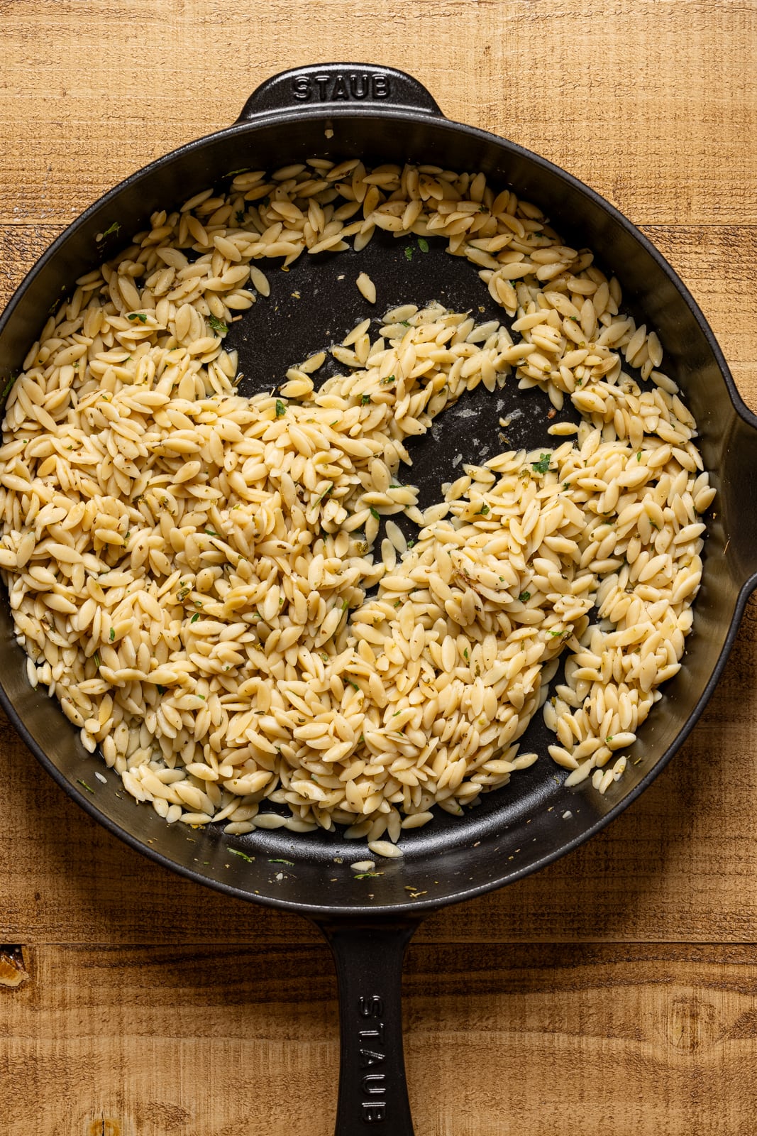 Cooked orzo in a black skillet. 