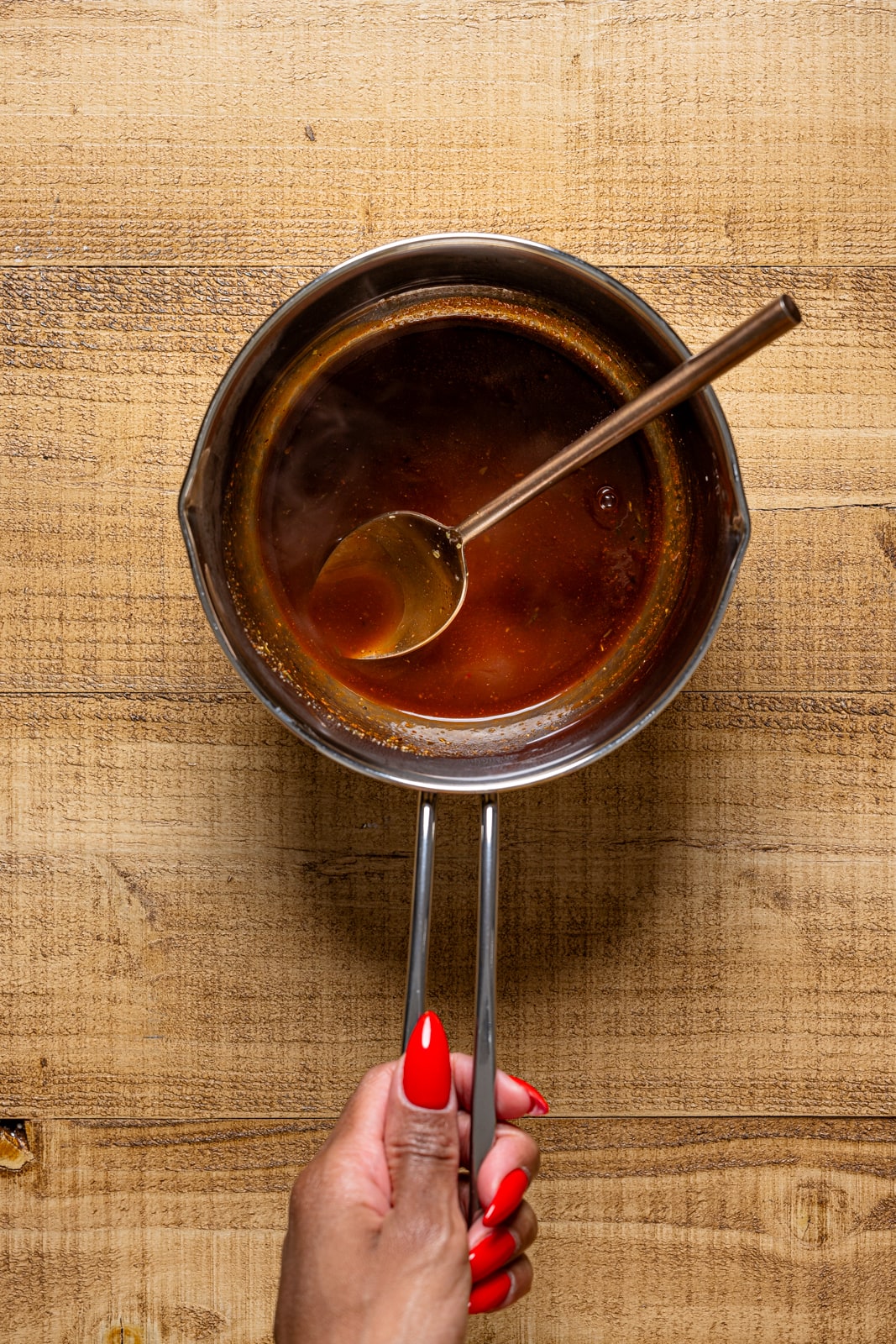 BBQ jerk sauce in a saucepan with a spoon.