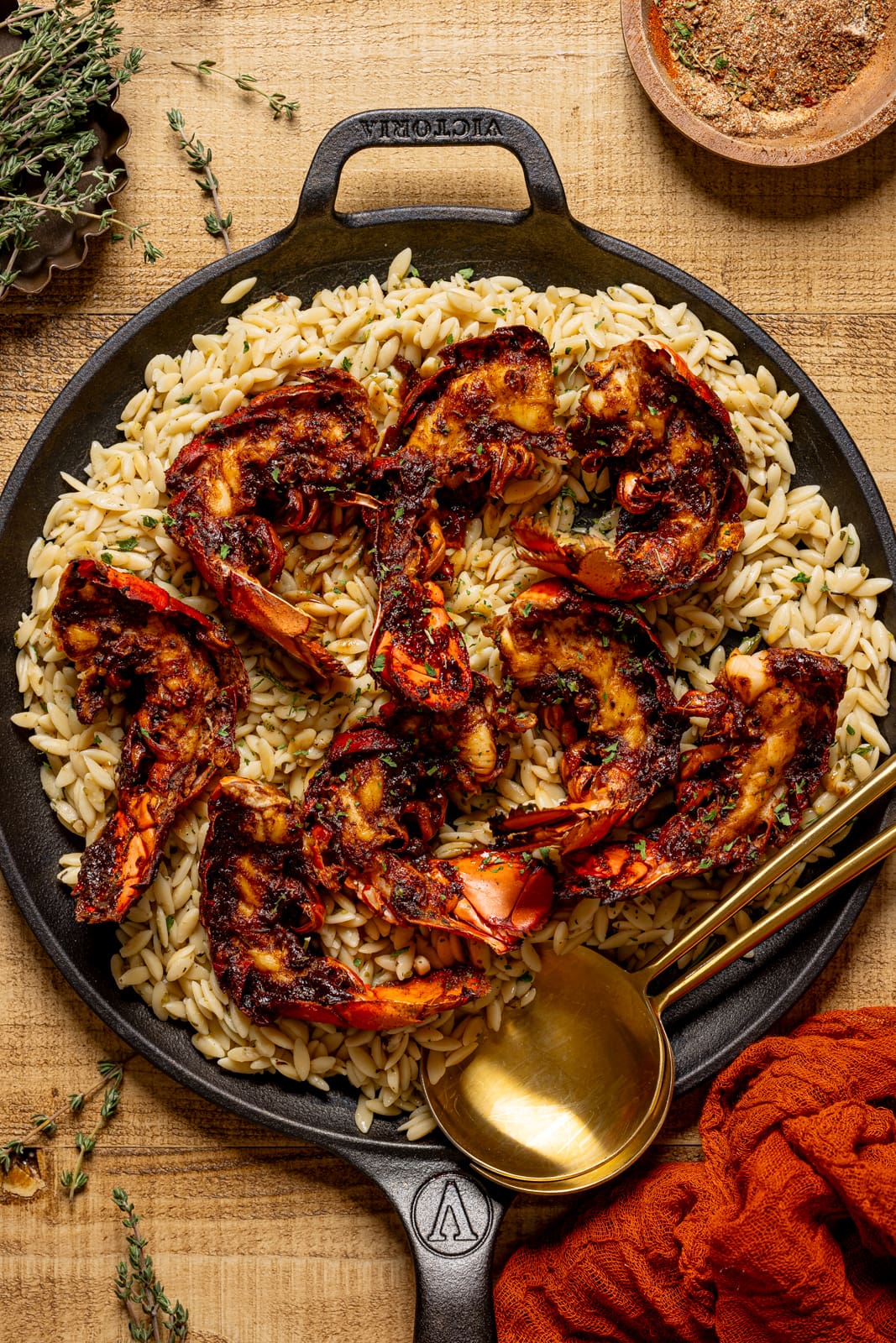 Lobster and orzo in skillet with gold serving spoons.