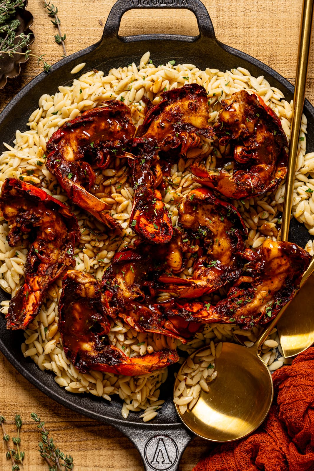 Lobster and orzo in a skillet with a gold serving spoon.