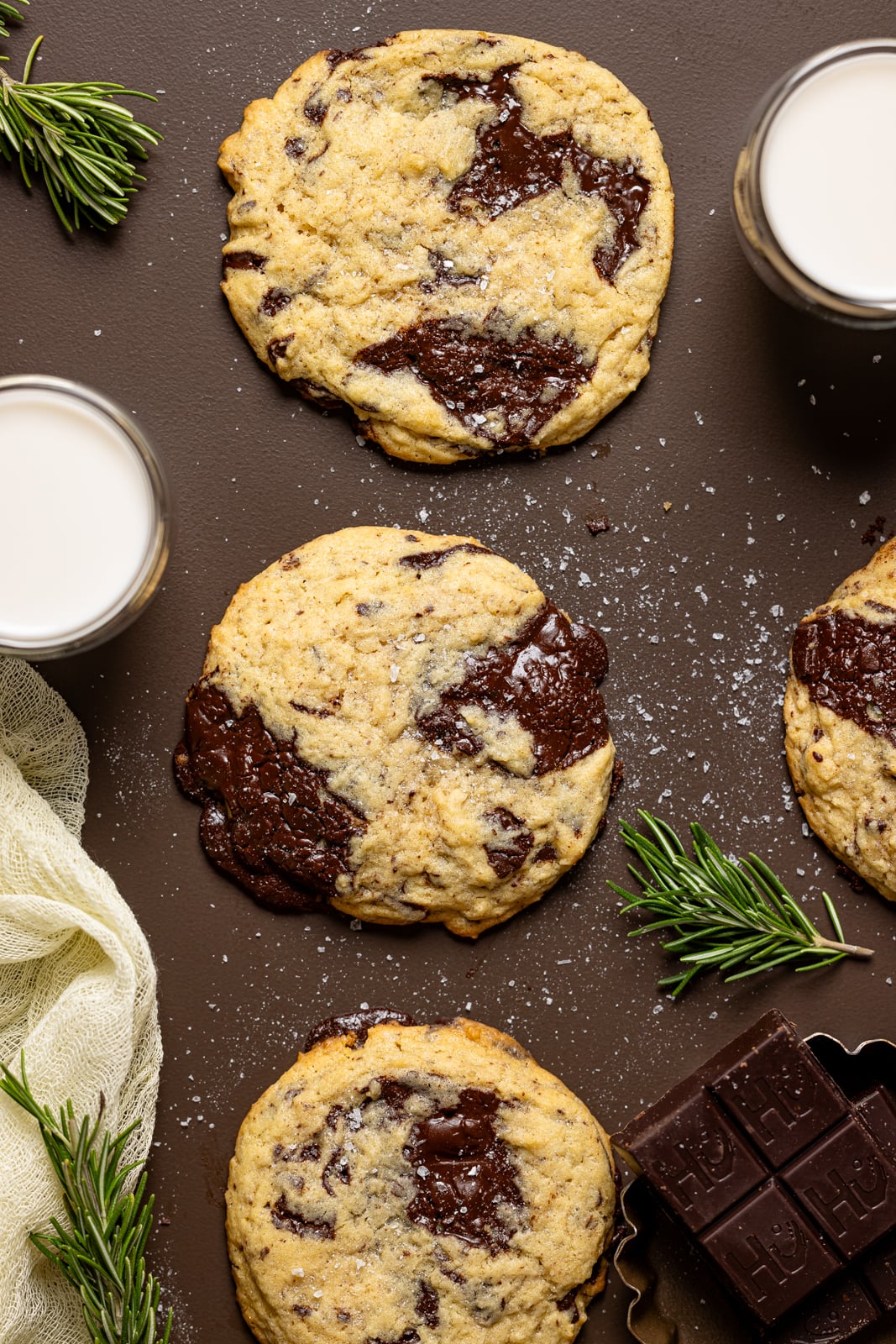 Cookies on a brown table with a glass of milk and chocolate. 