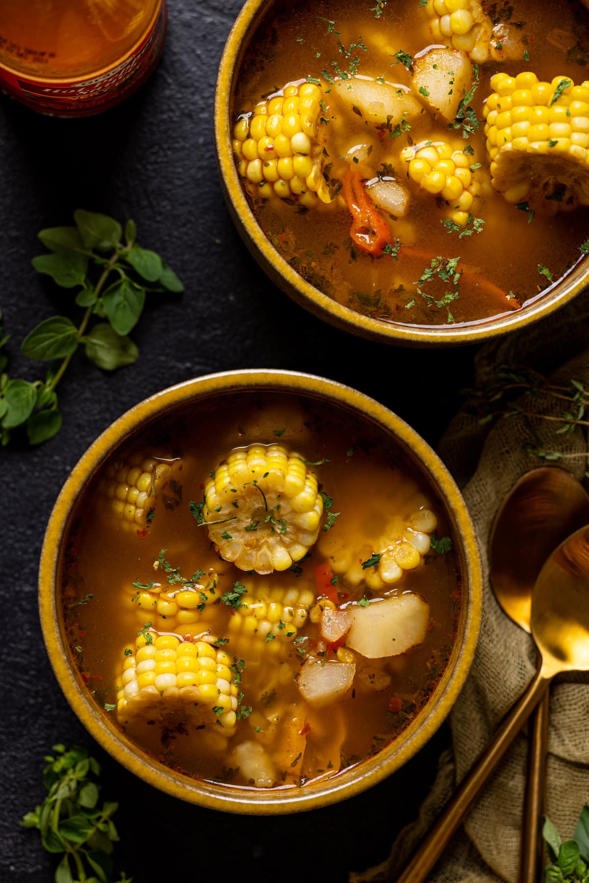 Two bowls of corn soup with spoons.
