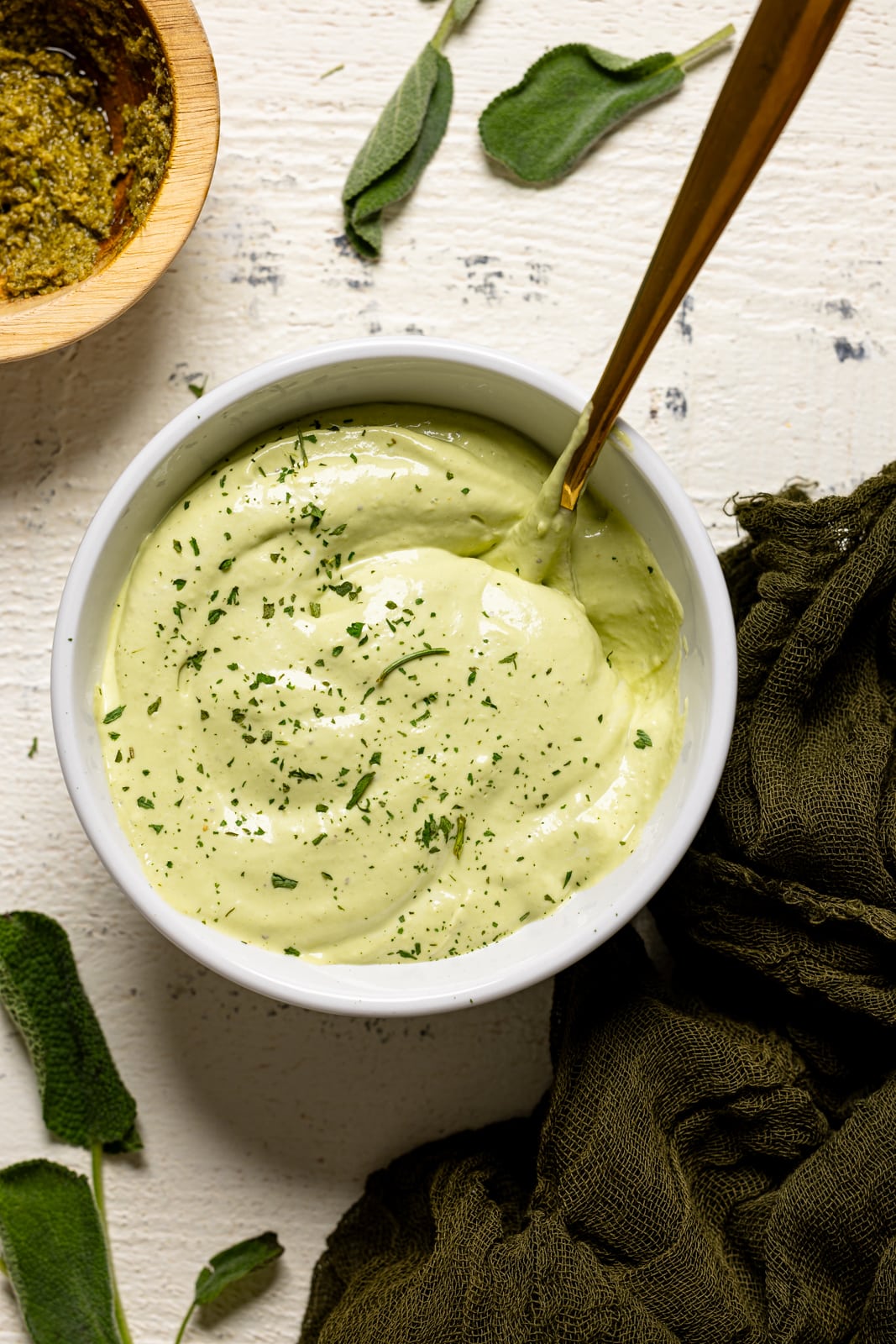 Sauce in a white bowl with a spoon on a white wood table.