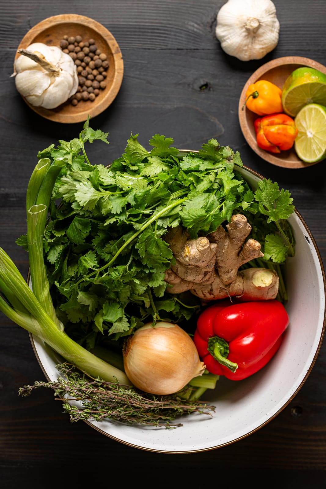 Bowl full of vegetables and ingredients on a black wood table.