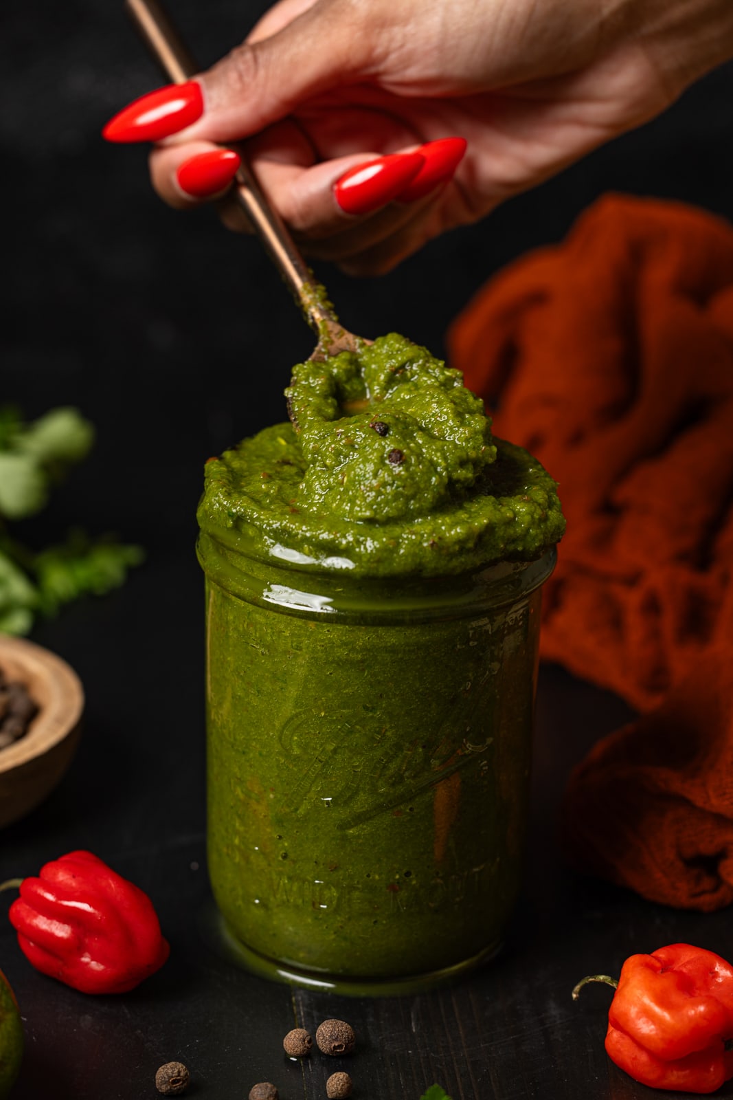 Green seasoning in a mason jar being held with a spoon.