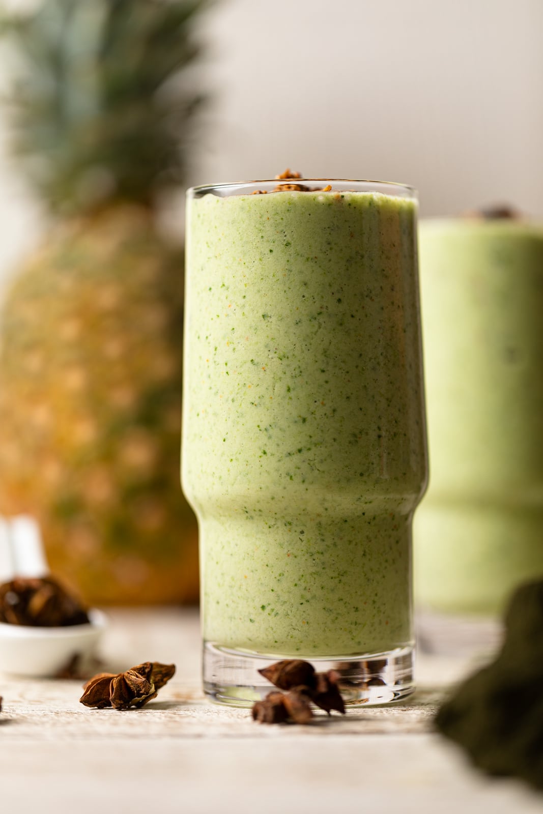 Two glasses of smoothies on a white wood table.