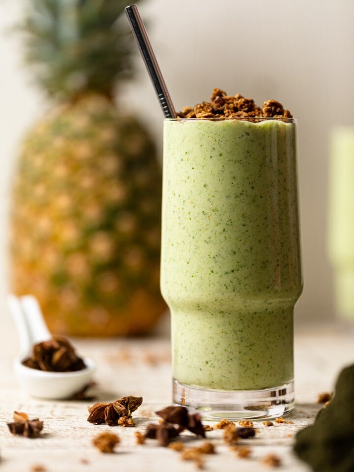 Glass of smoothie with a pineapple in the background and spices.