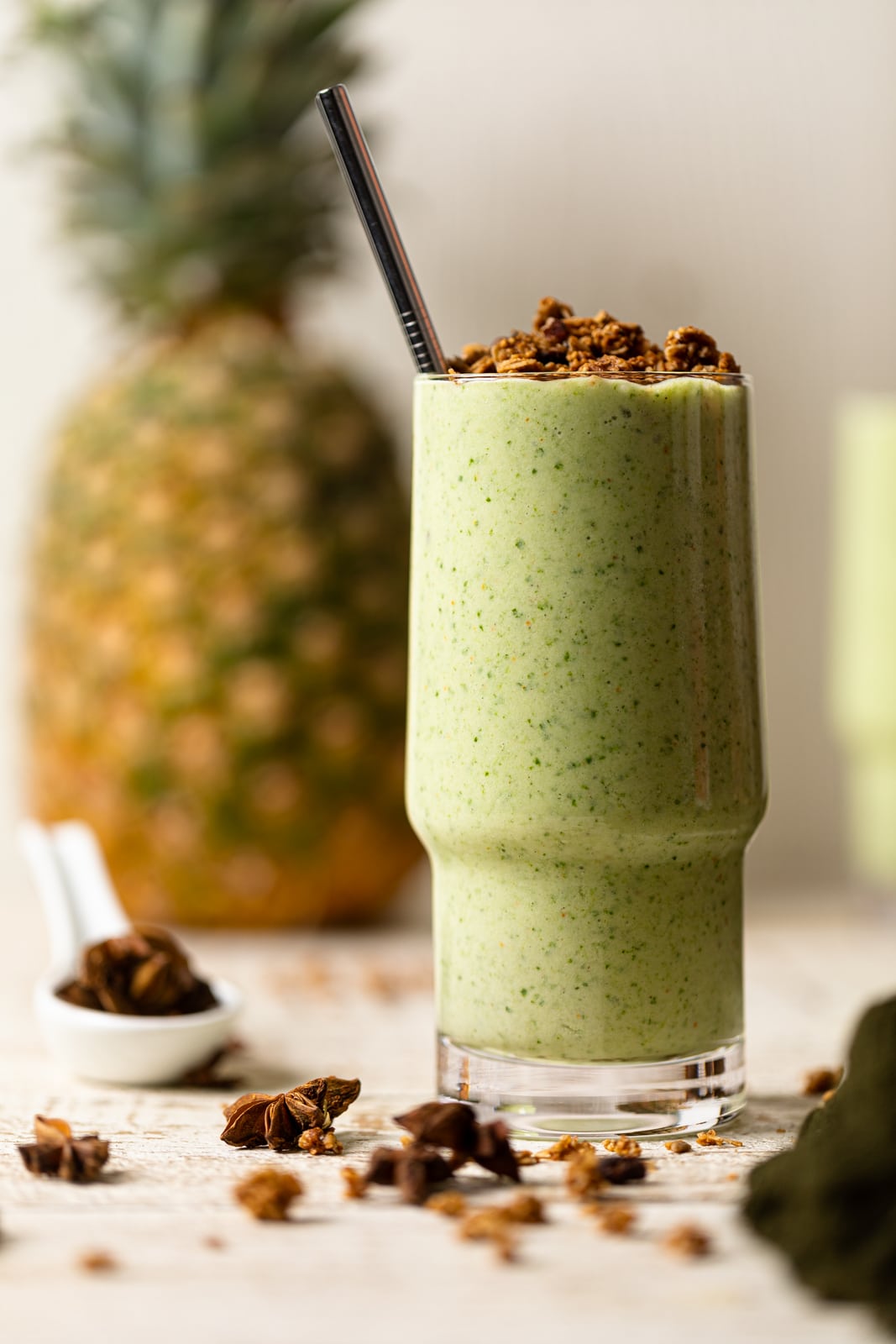 Glass of smoothie with a pineapple in the background and spices.