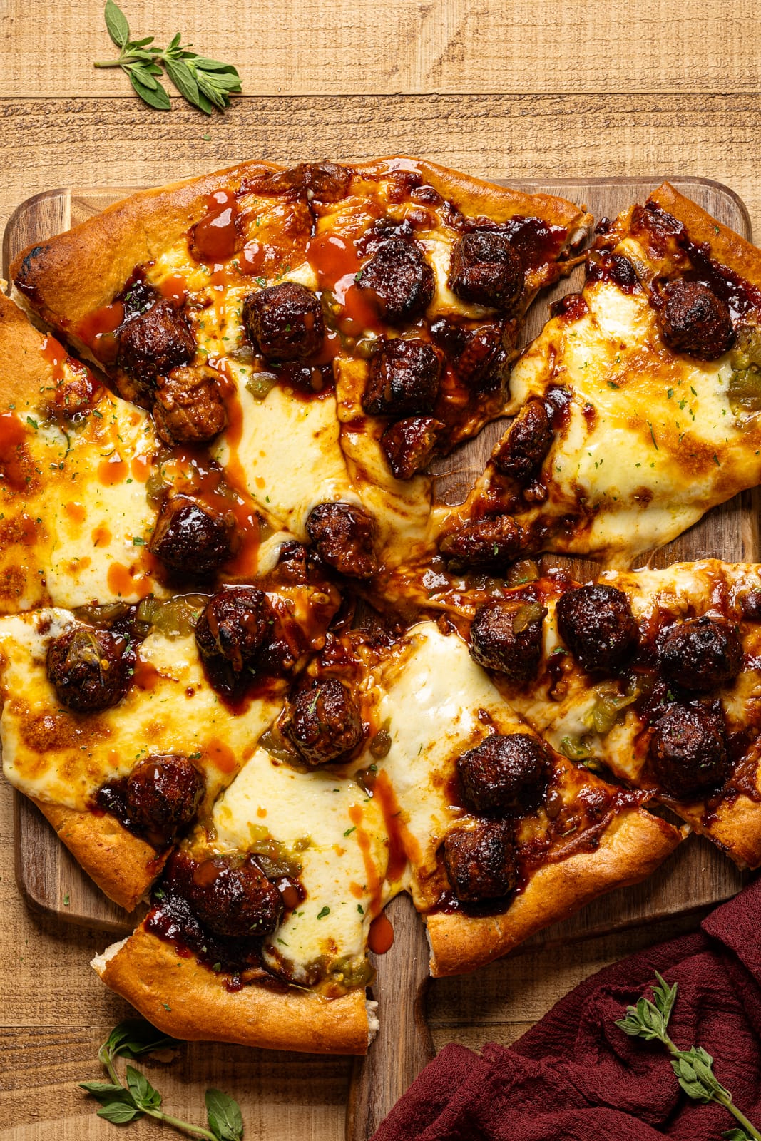 Meatball pizza sliced on a board.