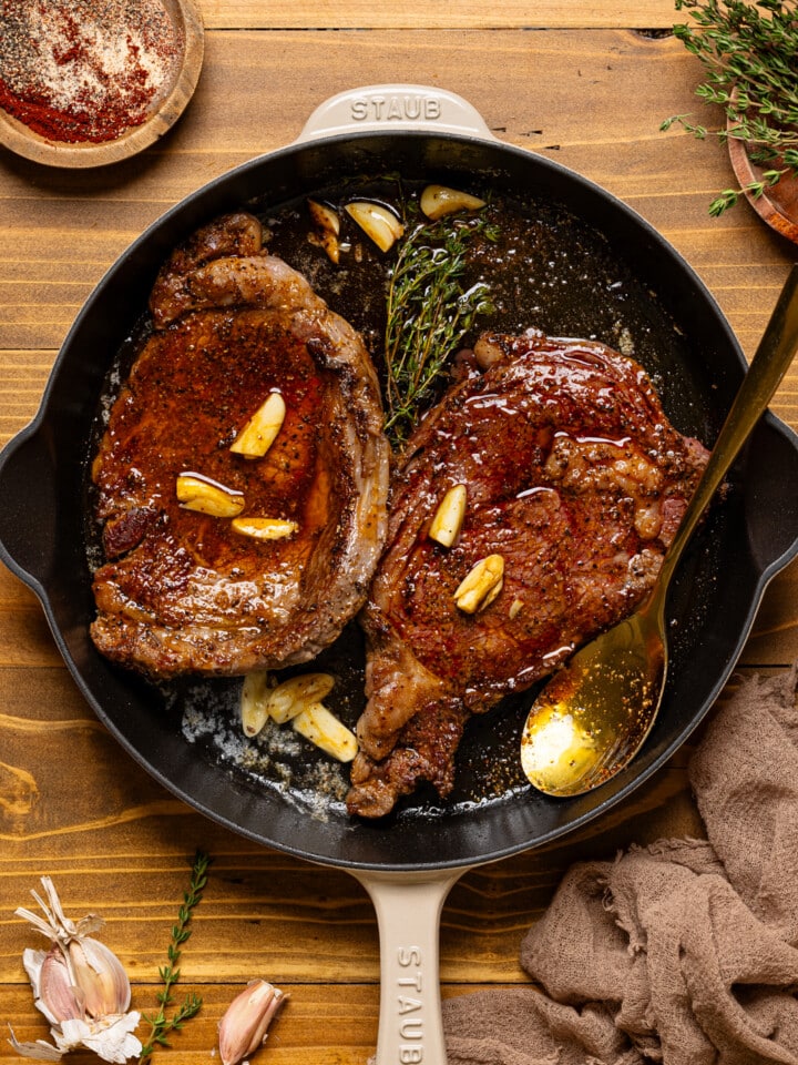 Fully seared steak with garlic, rosemary, and a spoon.