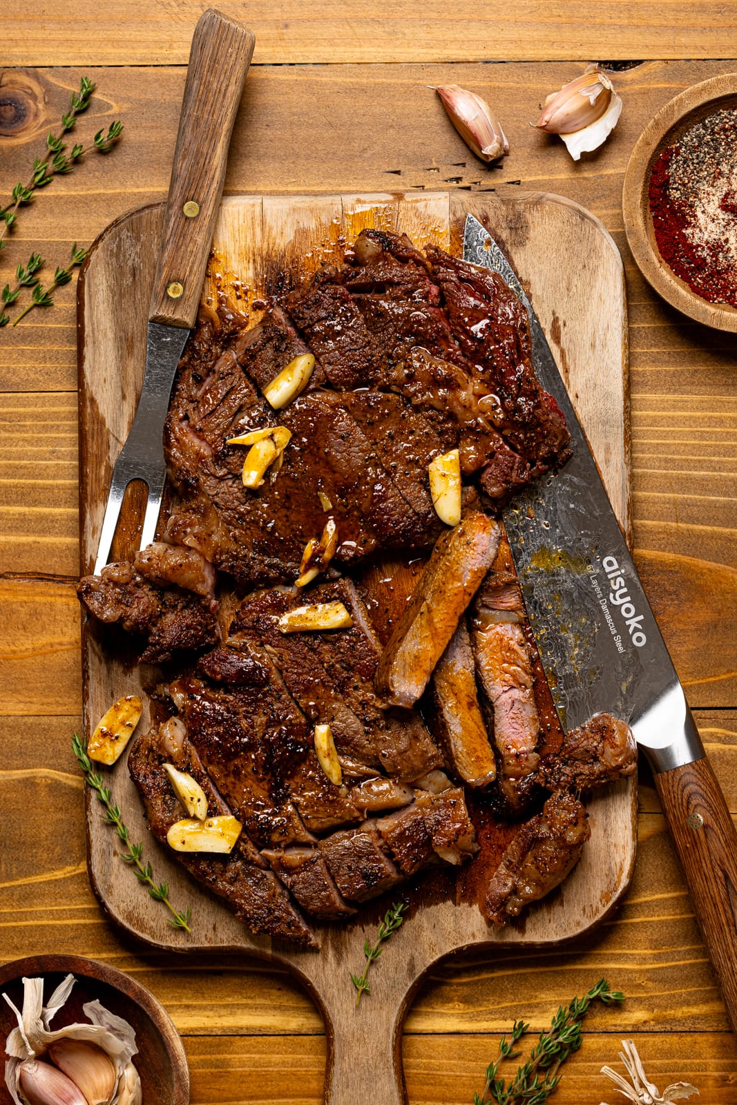 Sliced steak on a cutting board with a knife and fork.