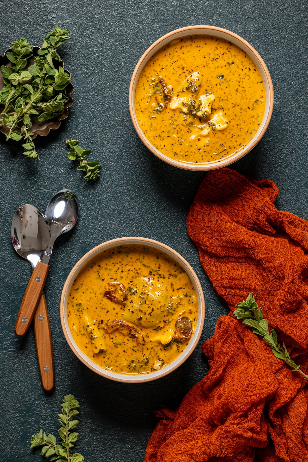 Bowls of soup with spoons and a red napkin.