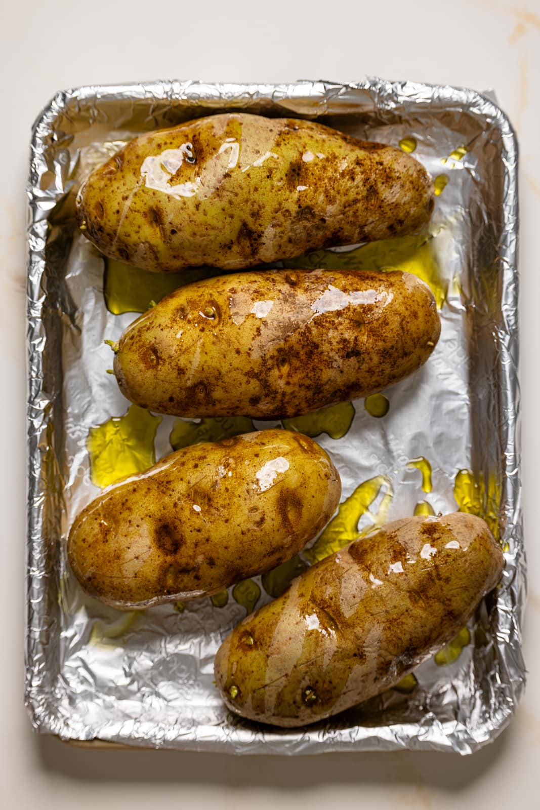 Potatoes on a baking sheet with foil paper and olive oil.