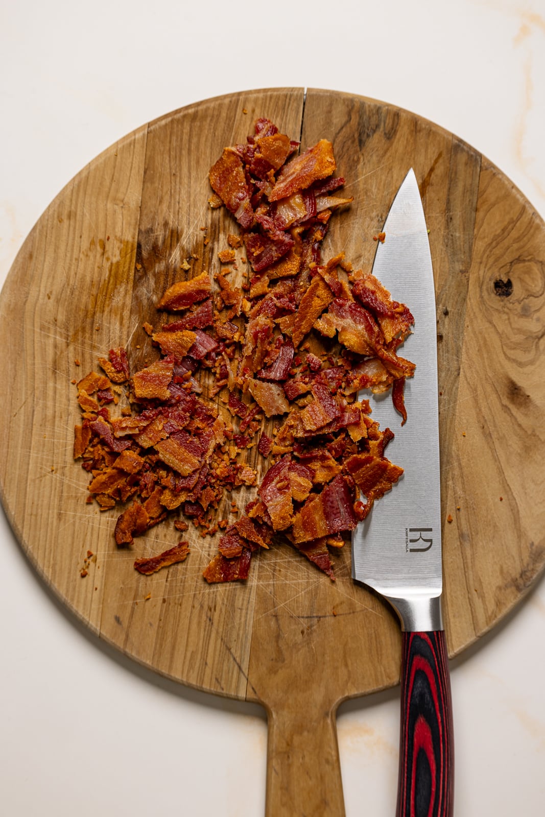 Chopped bacon on a cutting board with a knife.