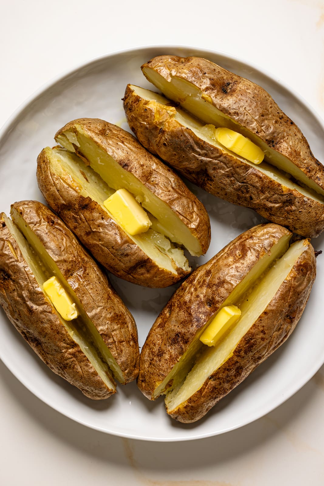 Slit baked potatoes with butter.