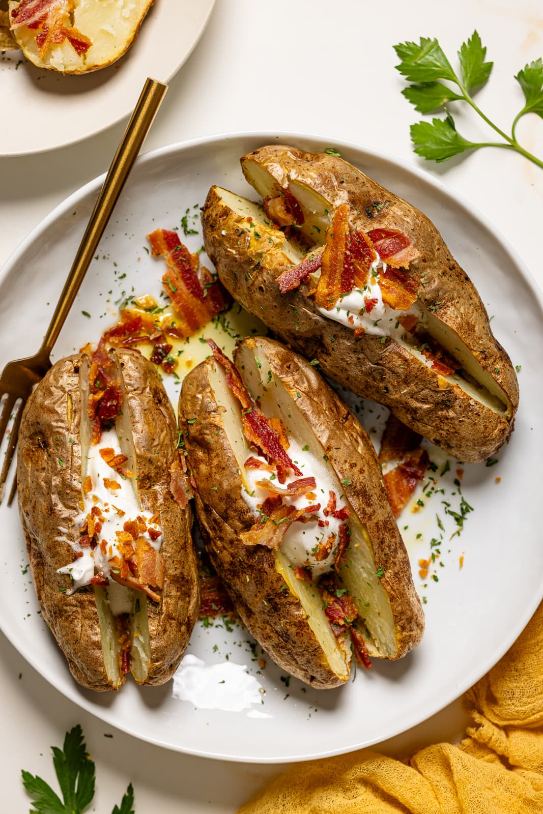 Baked potatoes with bacon on a white plate with a fork.