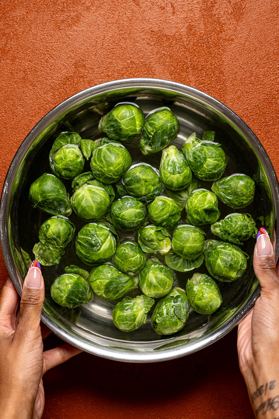 Soaked Brussels sprouts being held in a bowl.