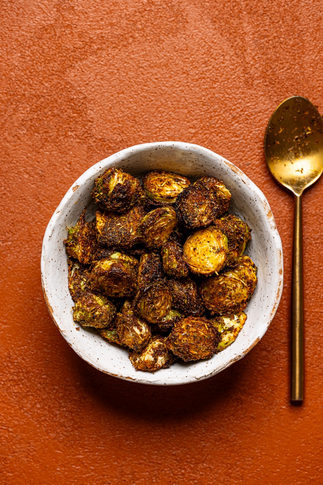 Brussels sprouts in a white bowl with a spoon.