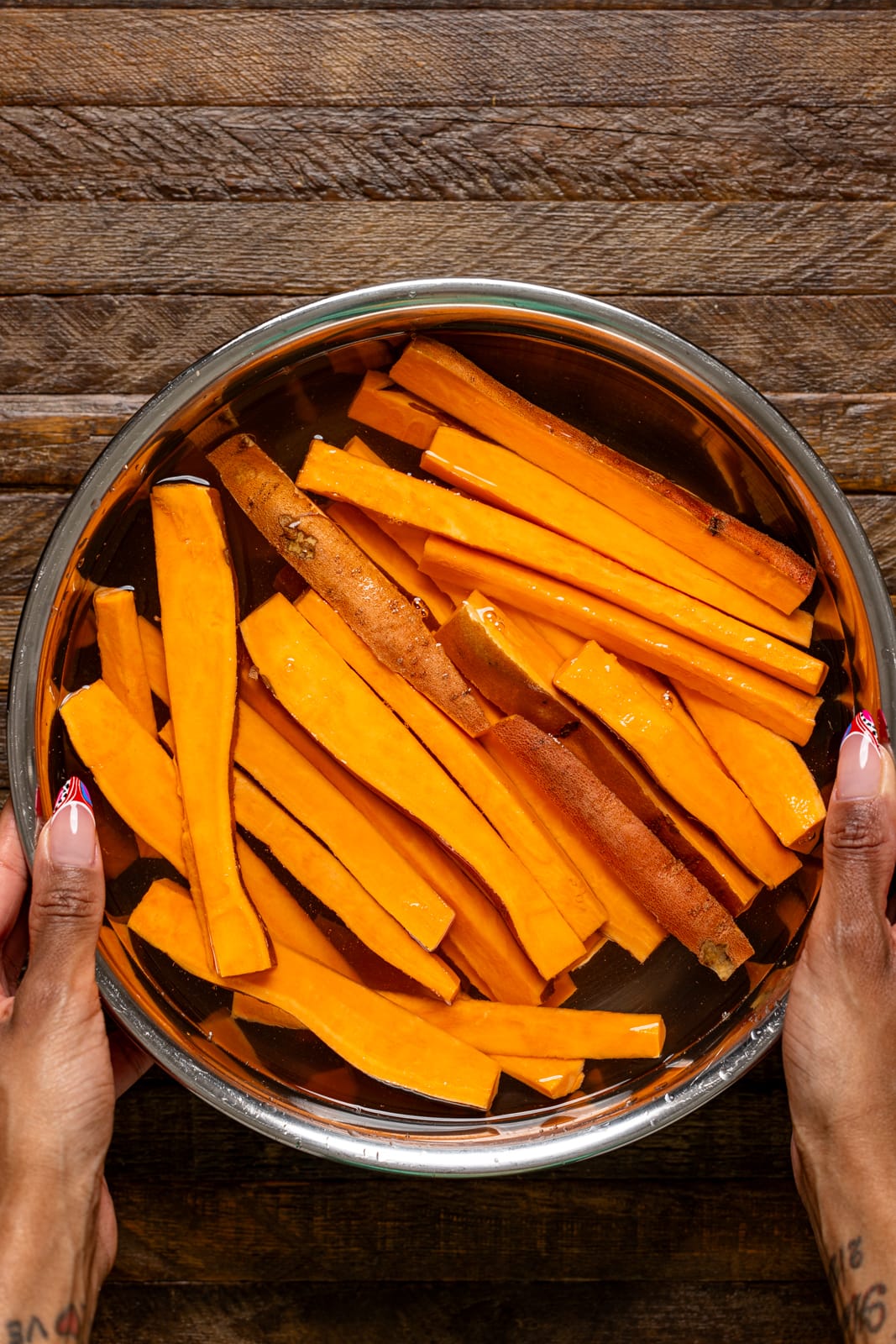 Cut sweet potatoes being soaked in a bowl with water.