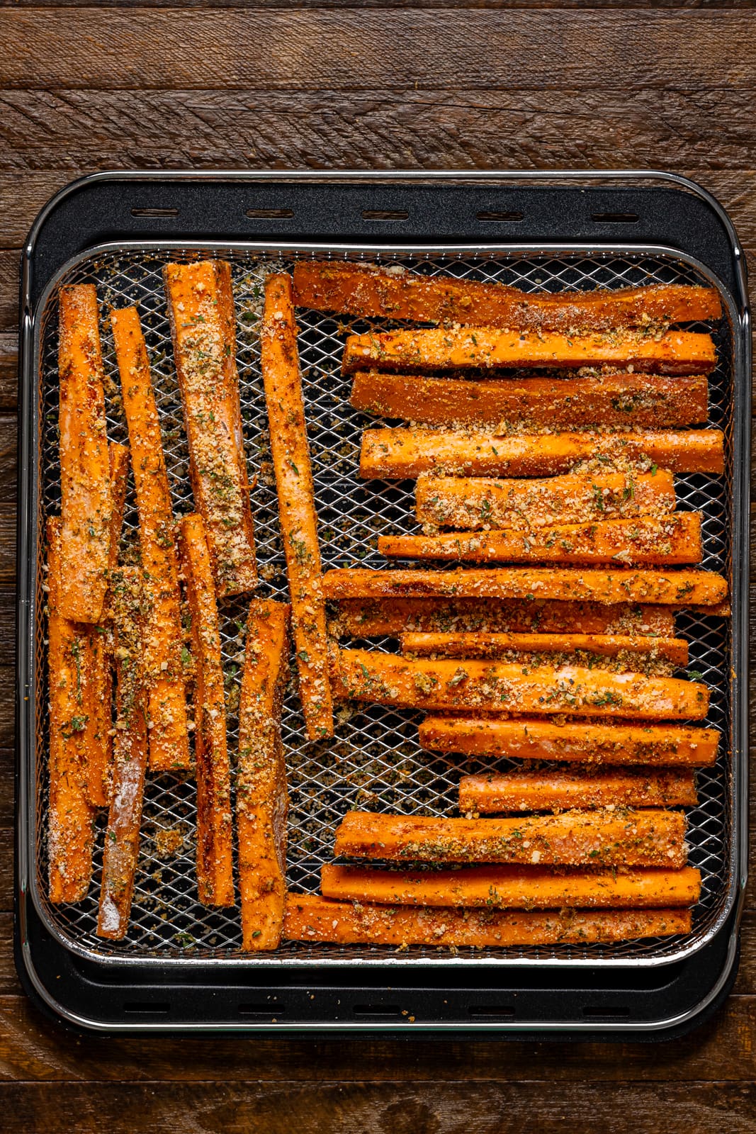 Fries lined on an air fryer basket. 