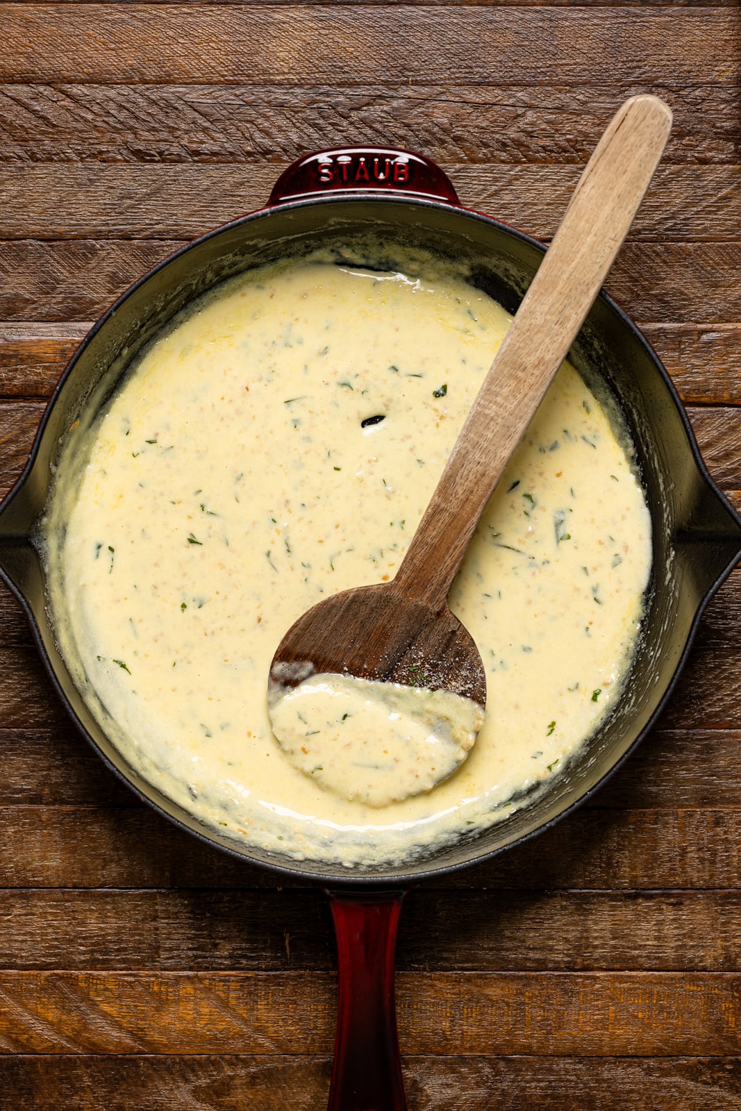 Parmesan garlic sauce in a skillet with a wooden spoon.