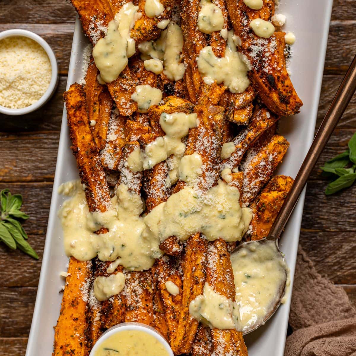 Fries on a white platter with sauce smothered on top.