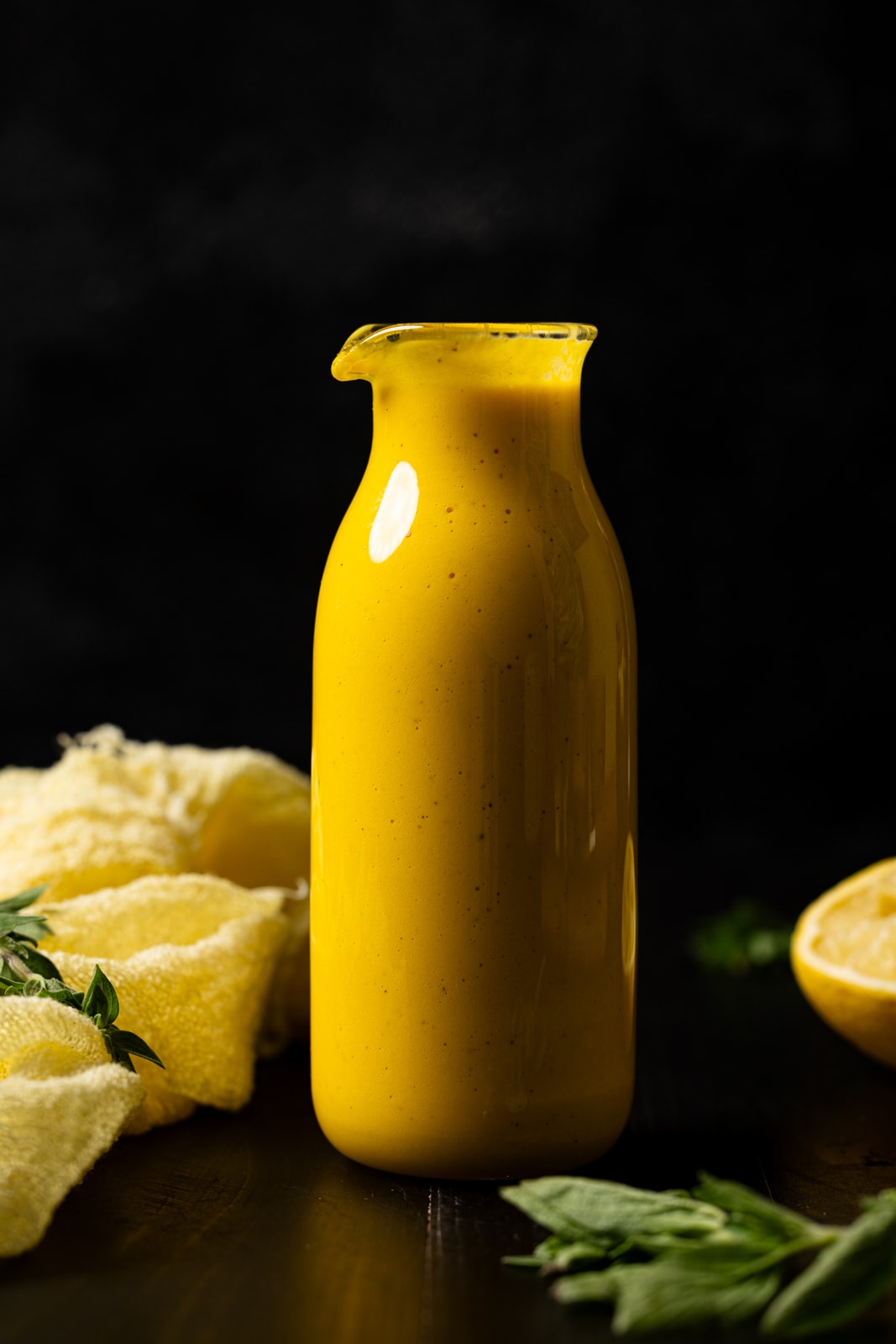 Dressing in a jar with a yellow napkin and lemon.