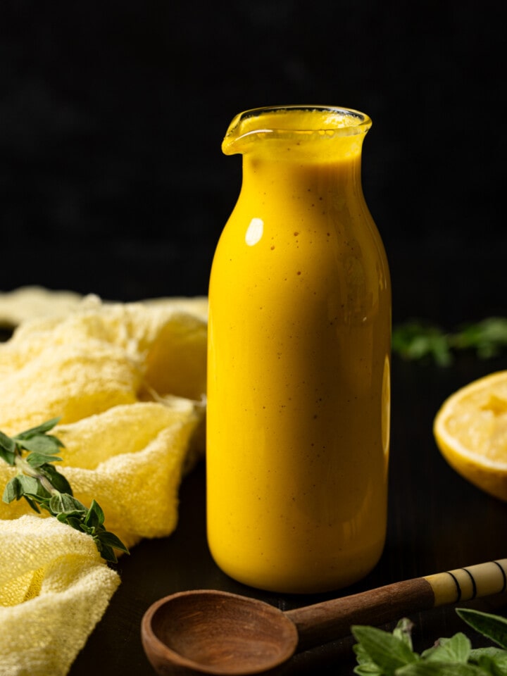 Dressing in a jar with lemon, wooden spoon, and napkin.