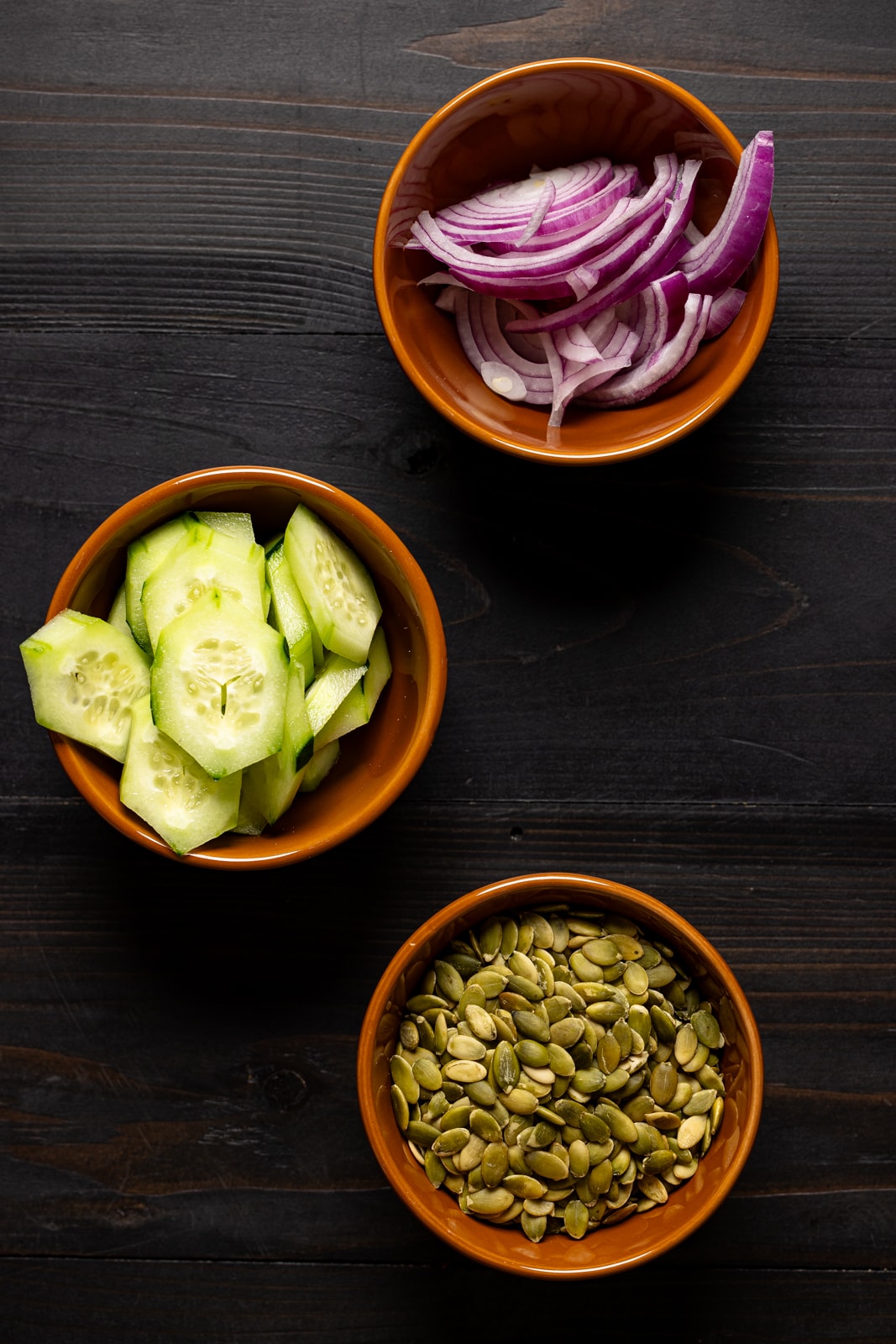 Topping ingredients in bowl on black wood table.