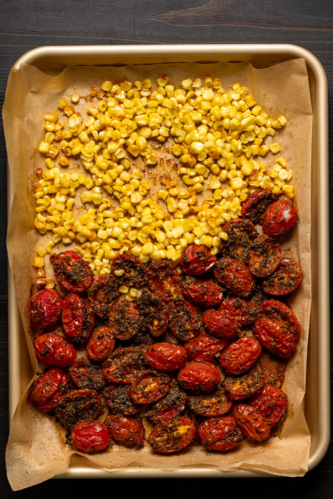 Roasted corn and tomatoes on a baking sheet with parchment. 