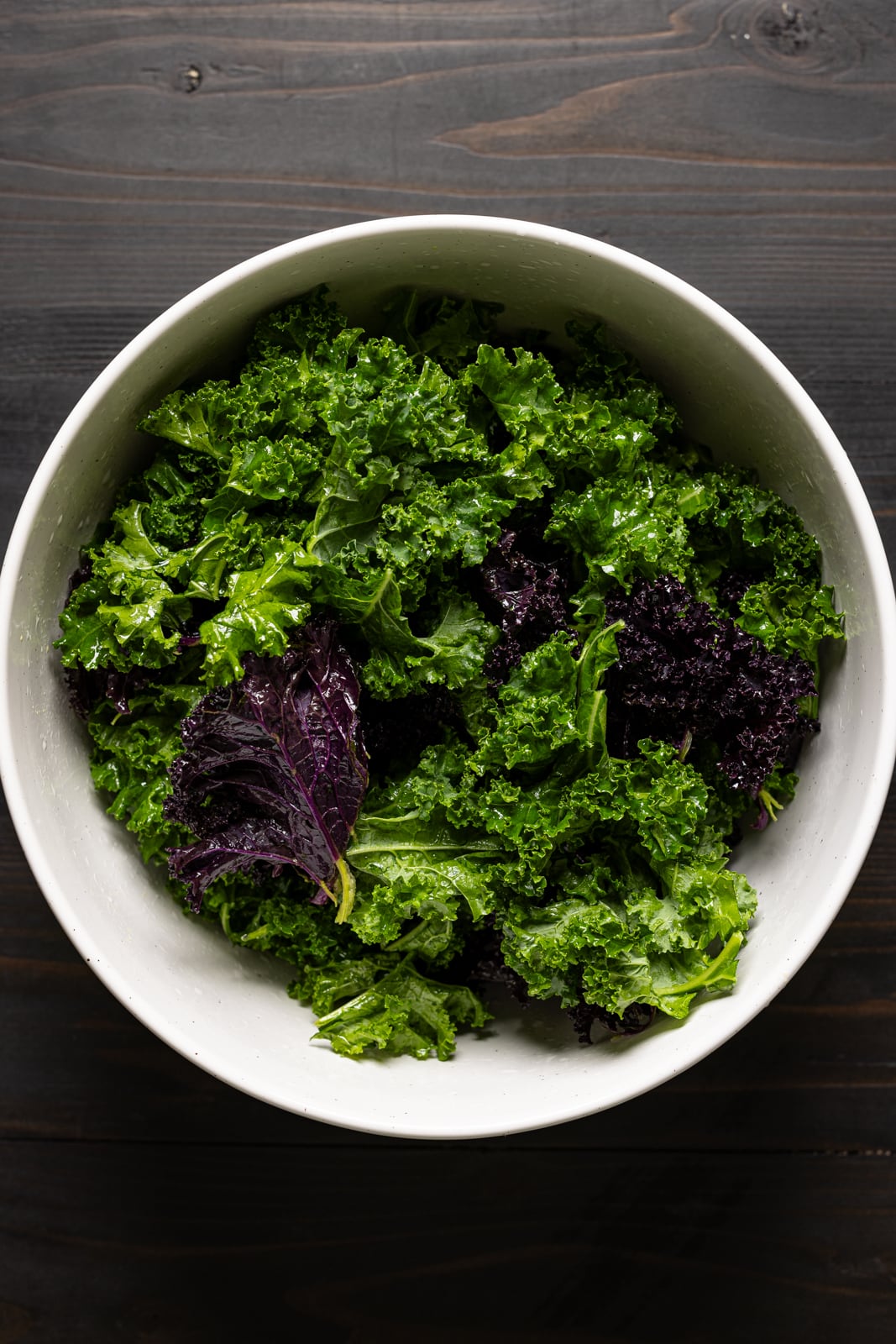 Kale in a bowl on a black wood table.