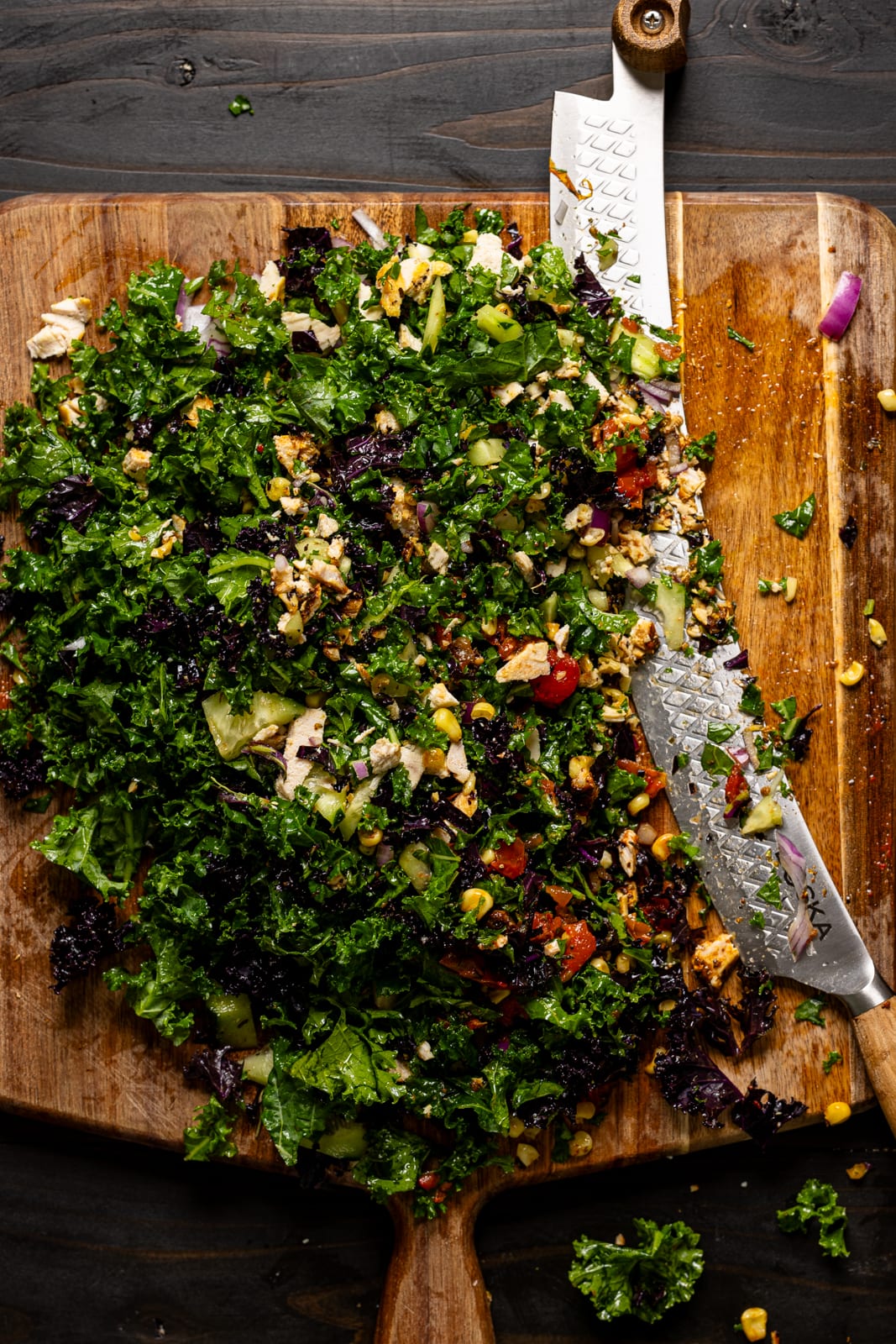 Chopped salad ingredients on a cutting board with a knife.