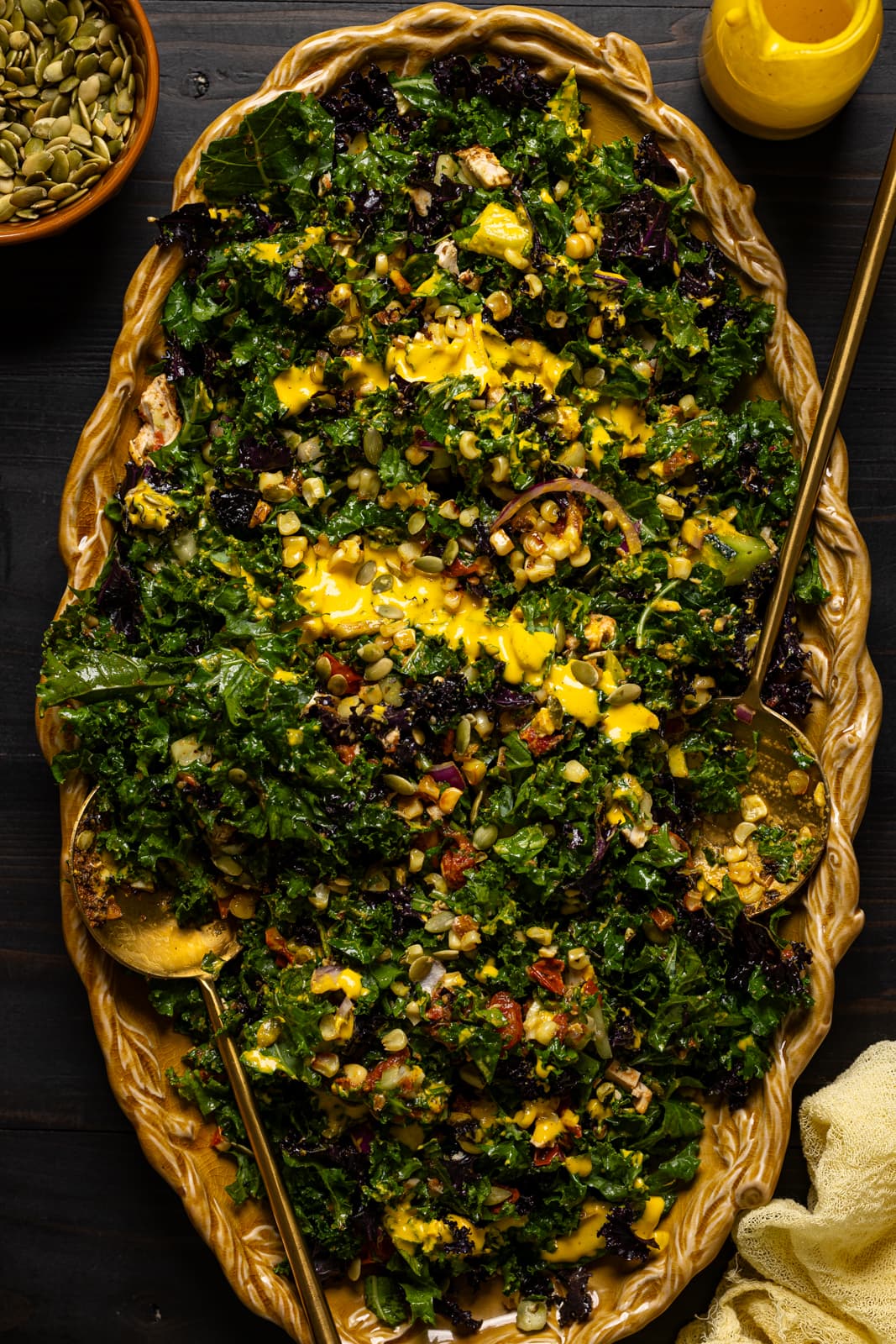 Chopped salad in a yellow platter with two serving spoons.