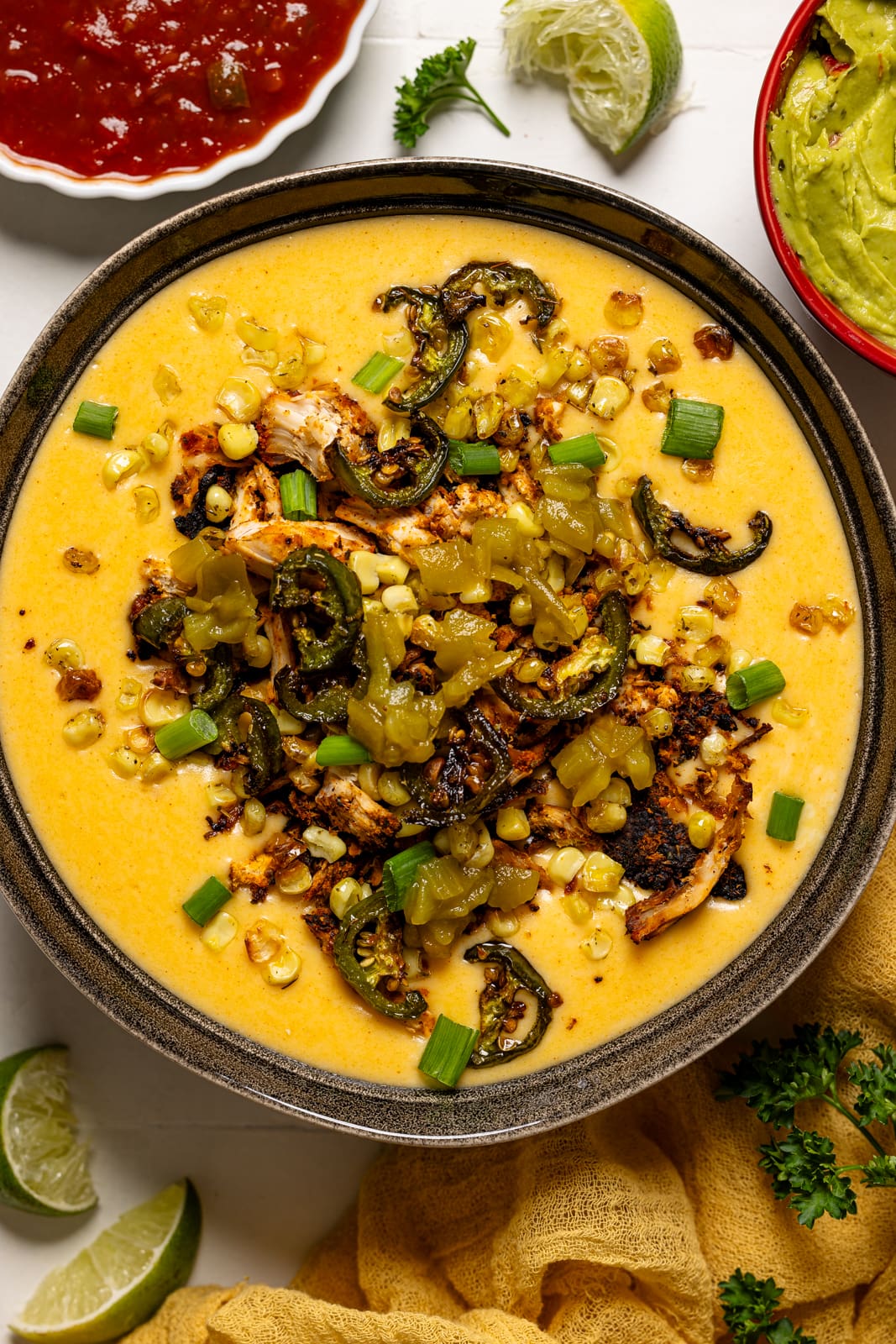 Up close shot of queso dip in a black bowl with salsa and lime.