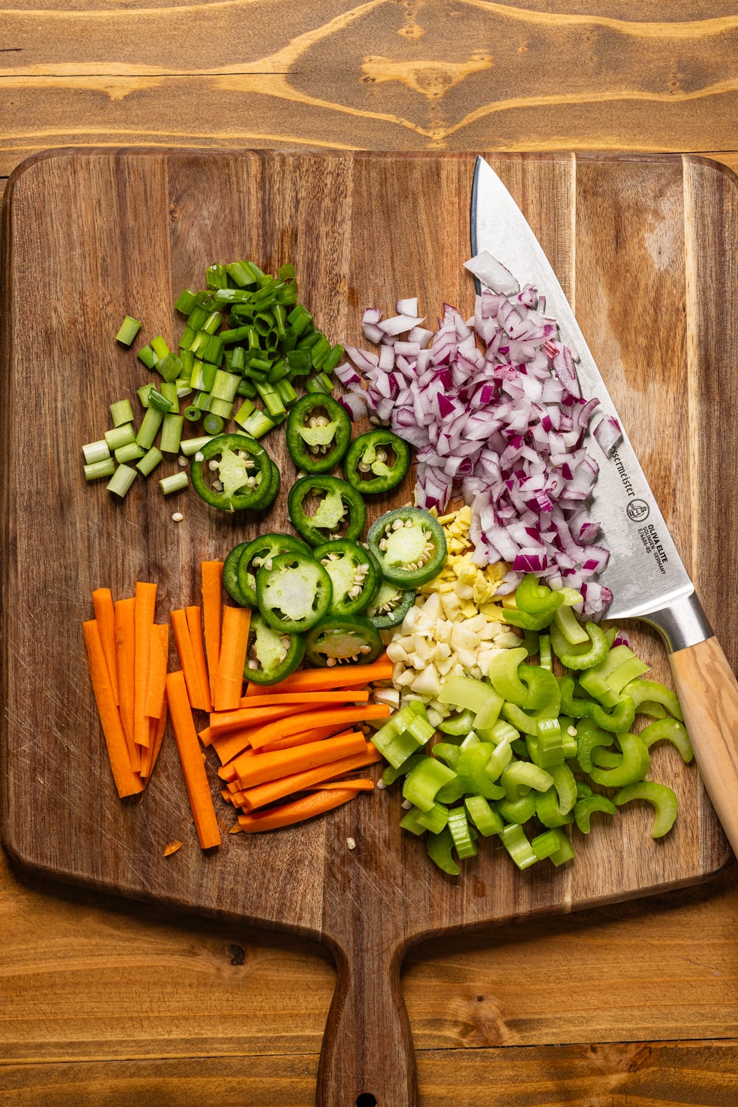 Chopped veggies on a cutting board with a knife.