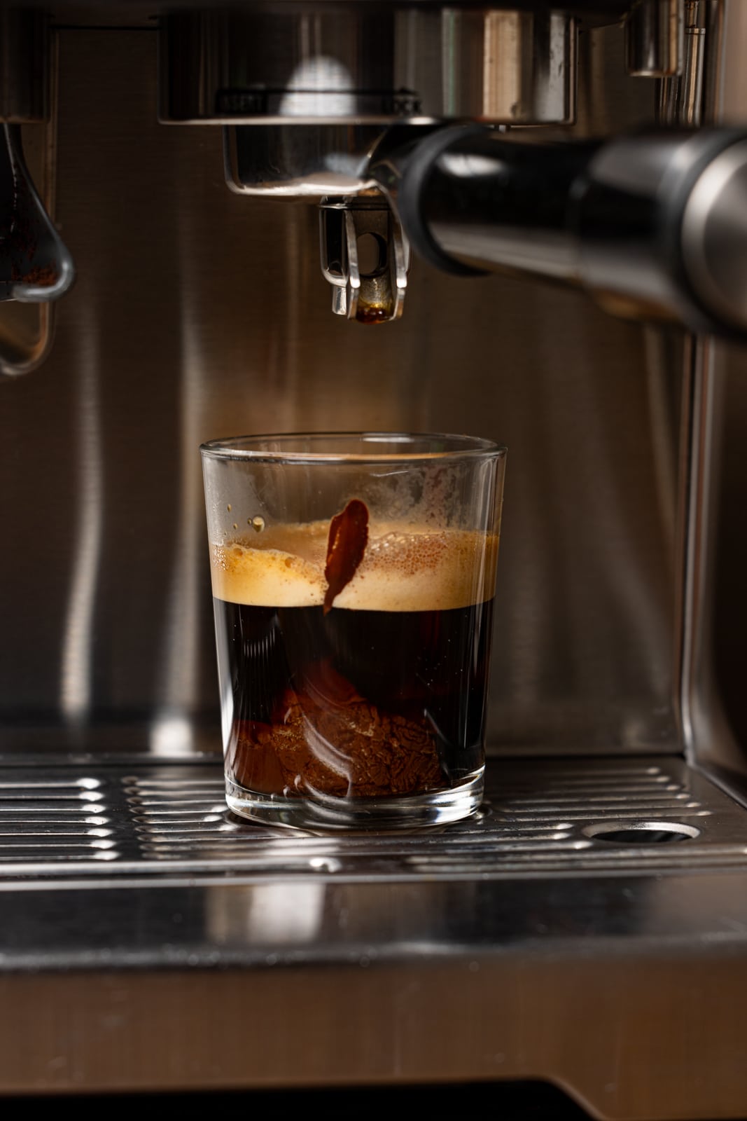 Freshly-brewed espresso in a glass on the machine.