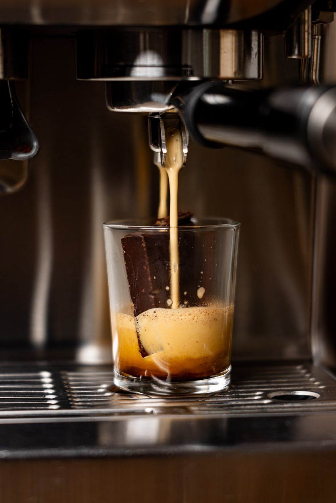 Drip of freshly-brewed espresso in a glass.