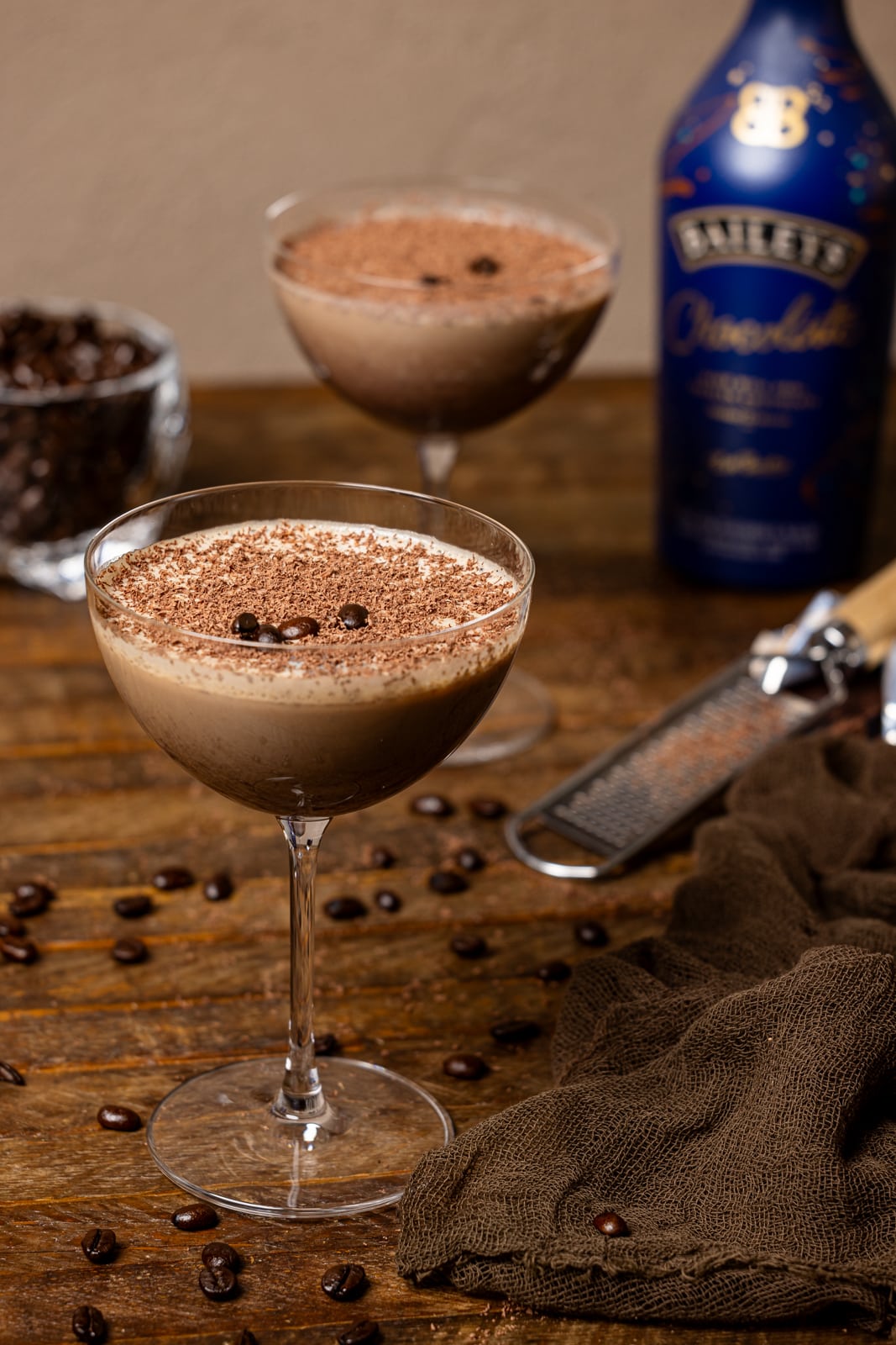 Two glasses of chocolate martinis with espresso beans and a grater.