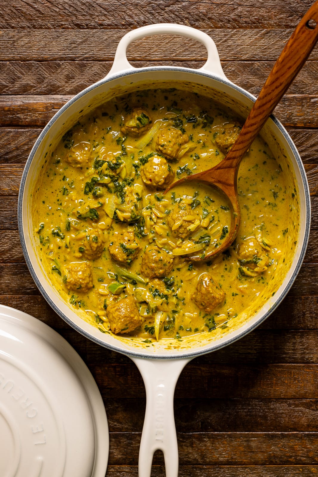 Curry soup in a pot on a brown wood table.