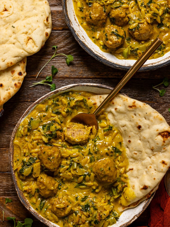 Bowl of soup with naan bread and spoon.