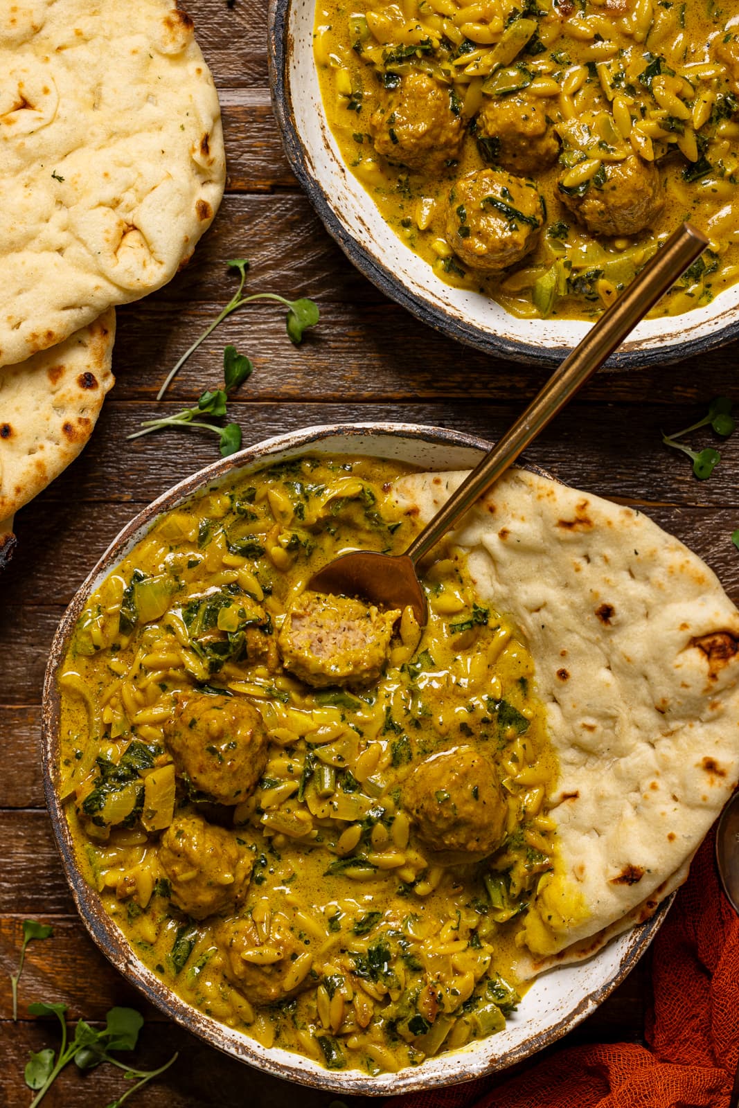 Bowl of soup with naan bread and spoon.