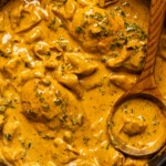 Up close of creamy chicken and tortellini in a skillet with a wooden spoon.