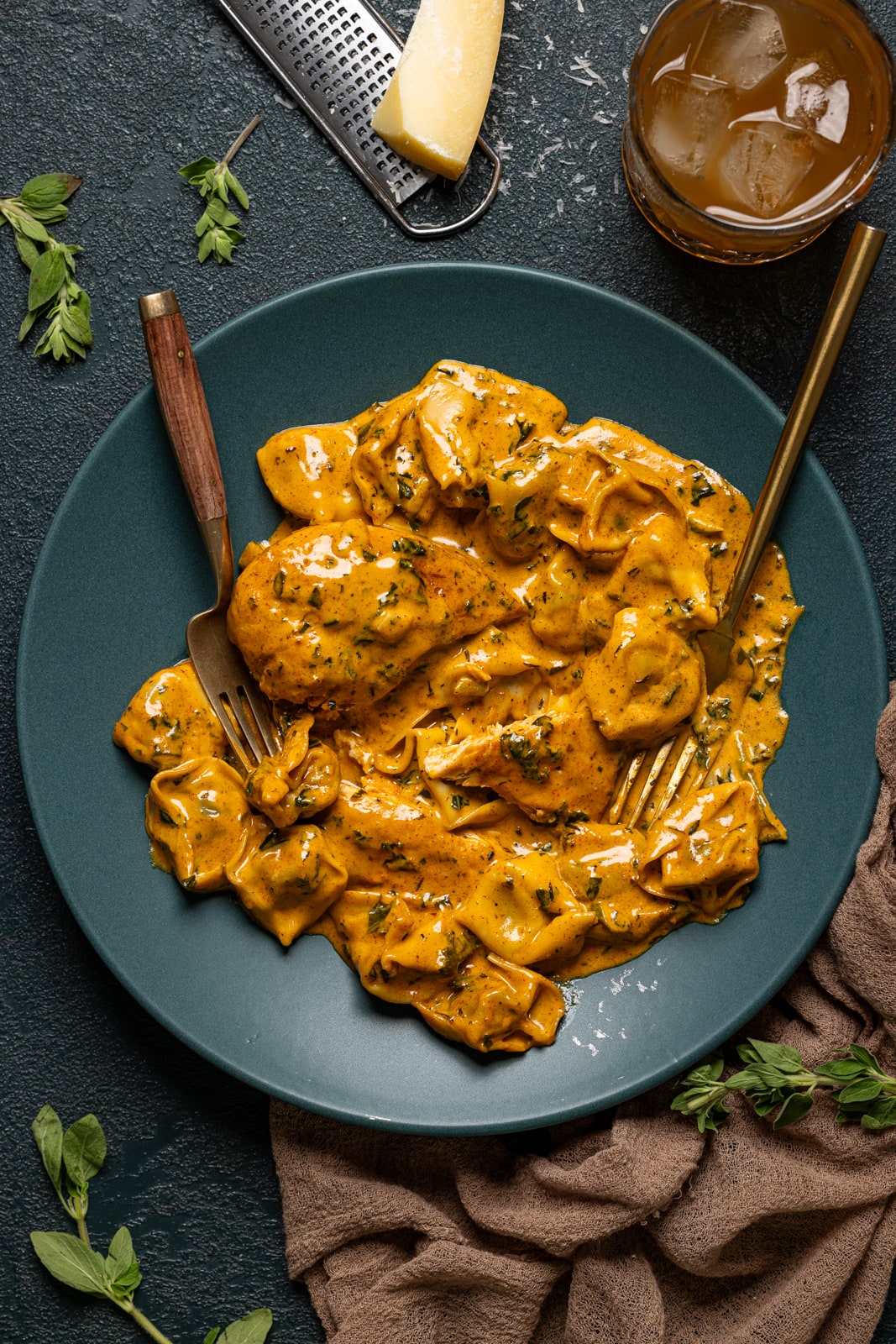 Creamy chicken dish on a plate with two forks and parmesan.