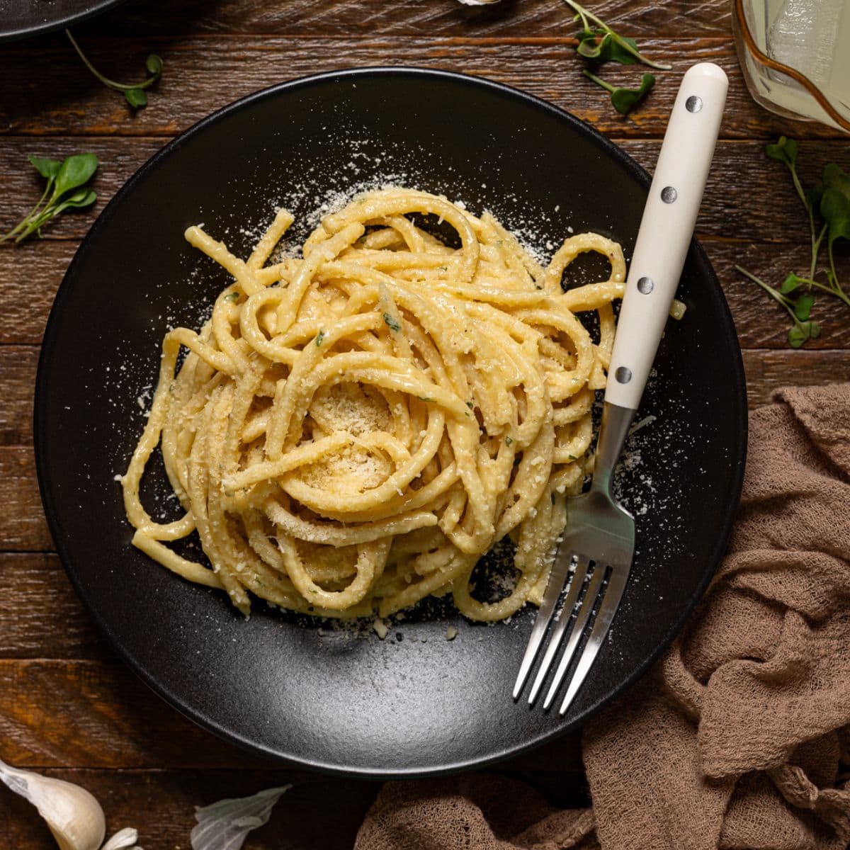 Two plates of pasta on a brown wood table with a fork.