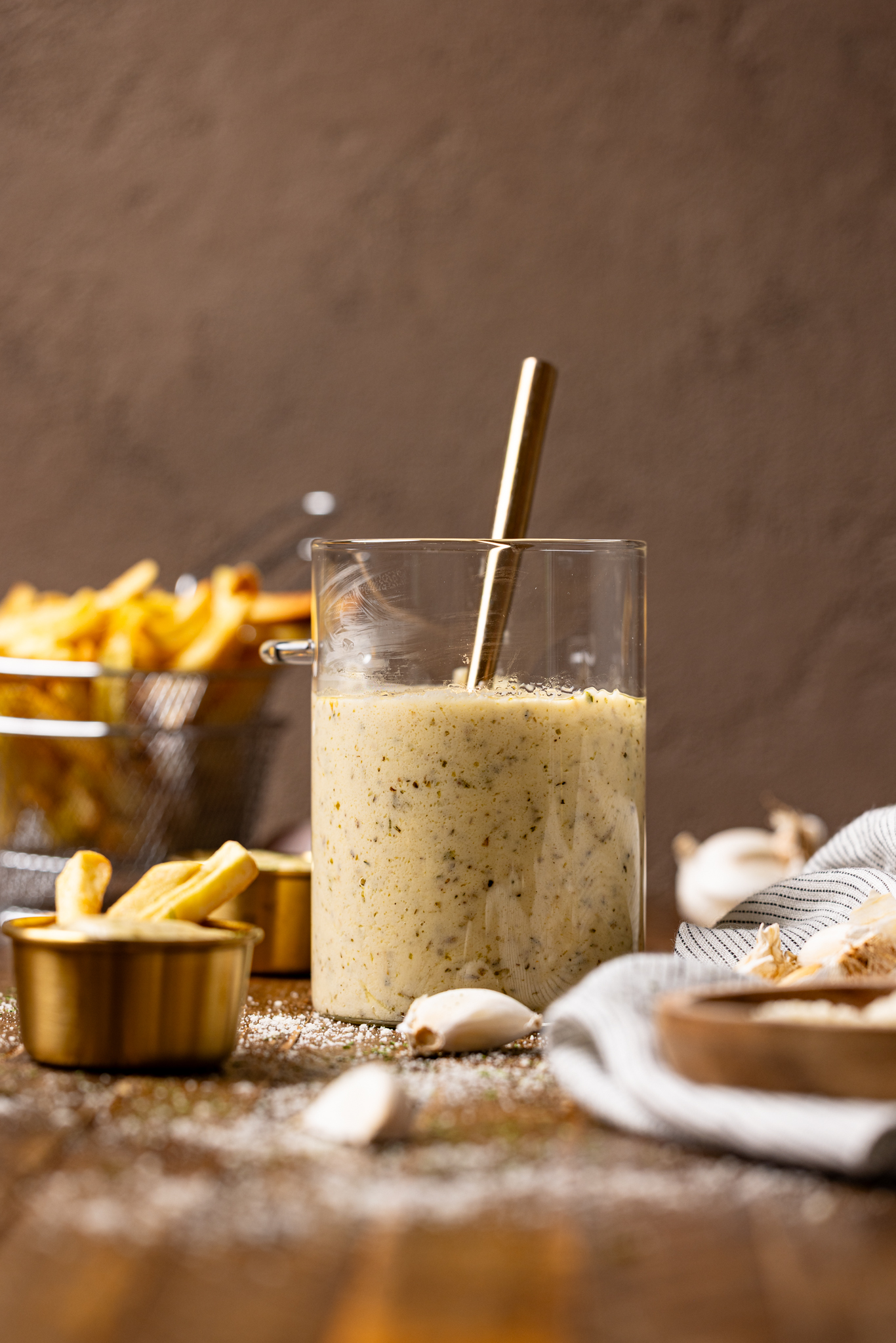 Image of garlic parmesan sauce in a jar with a spoon and fries.