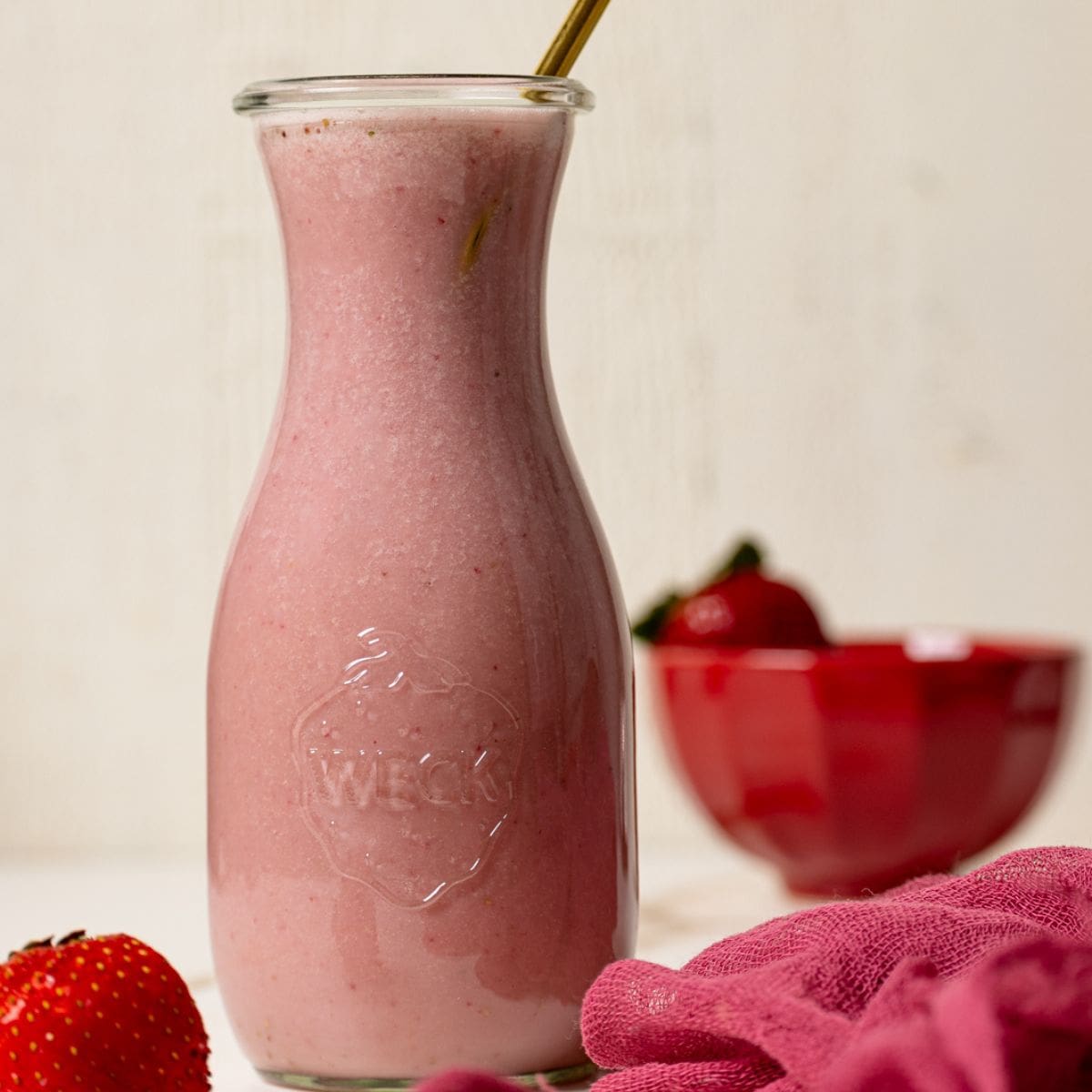 Strawberry milk in a jar with a straw and fresh strawberries.