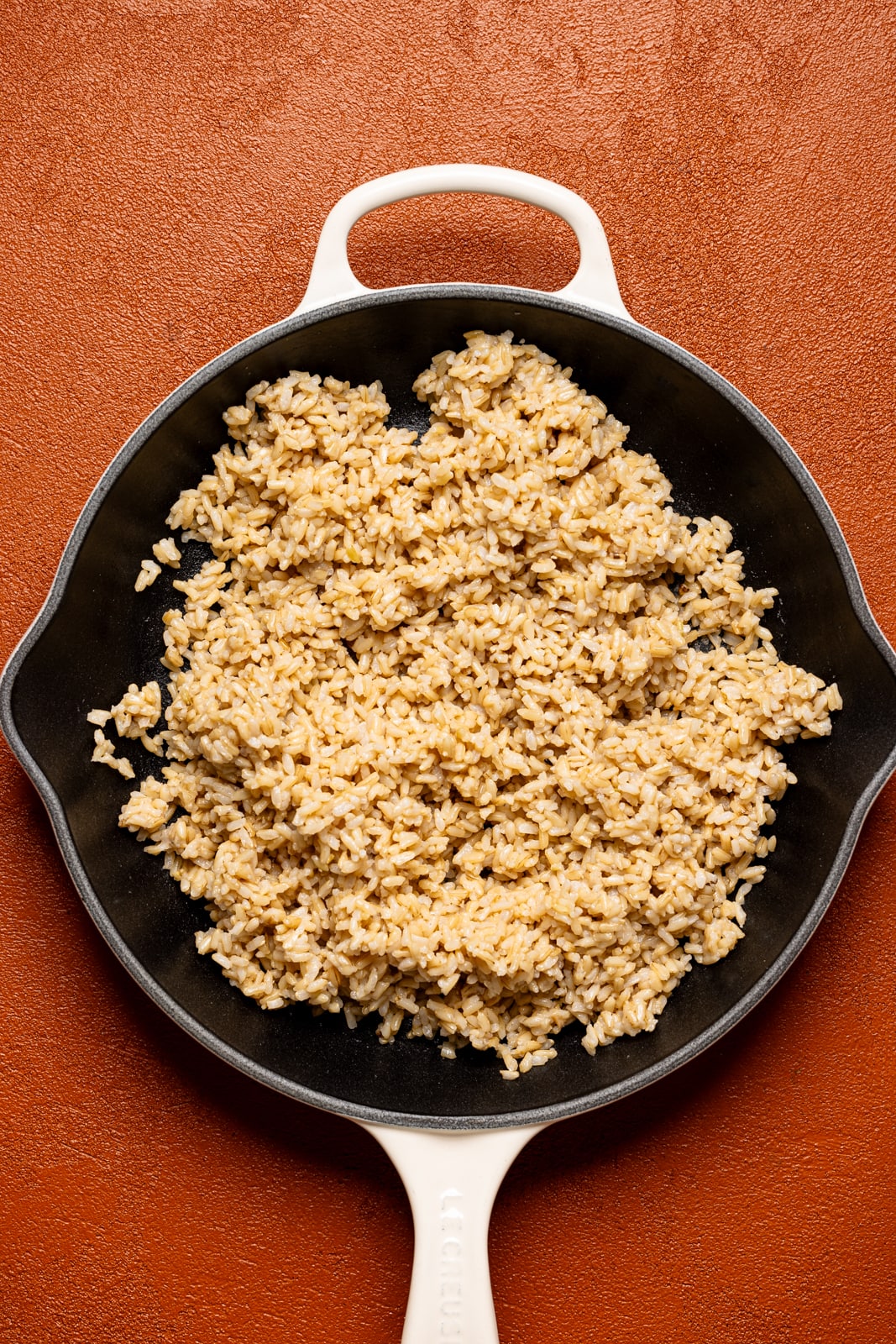 Cooked brown rice in a white skillet. 