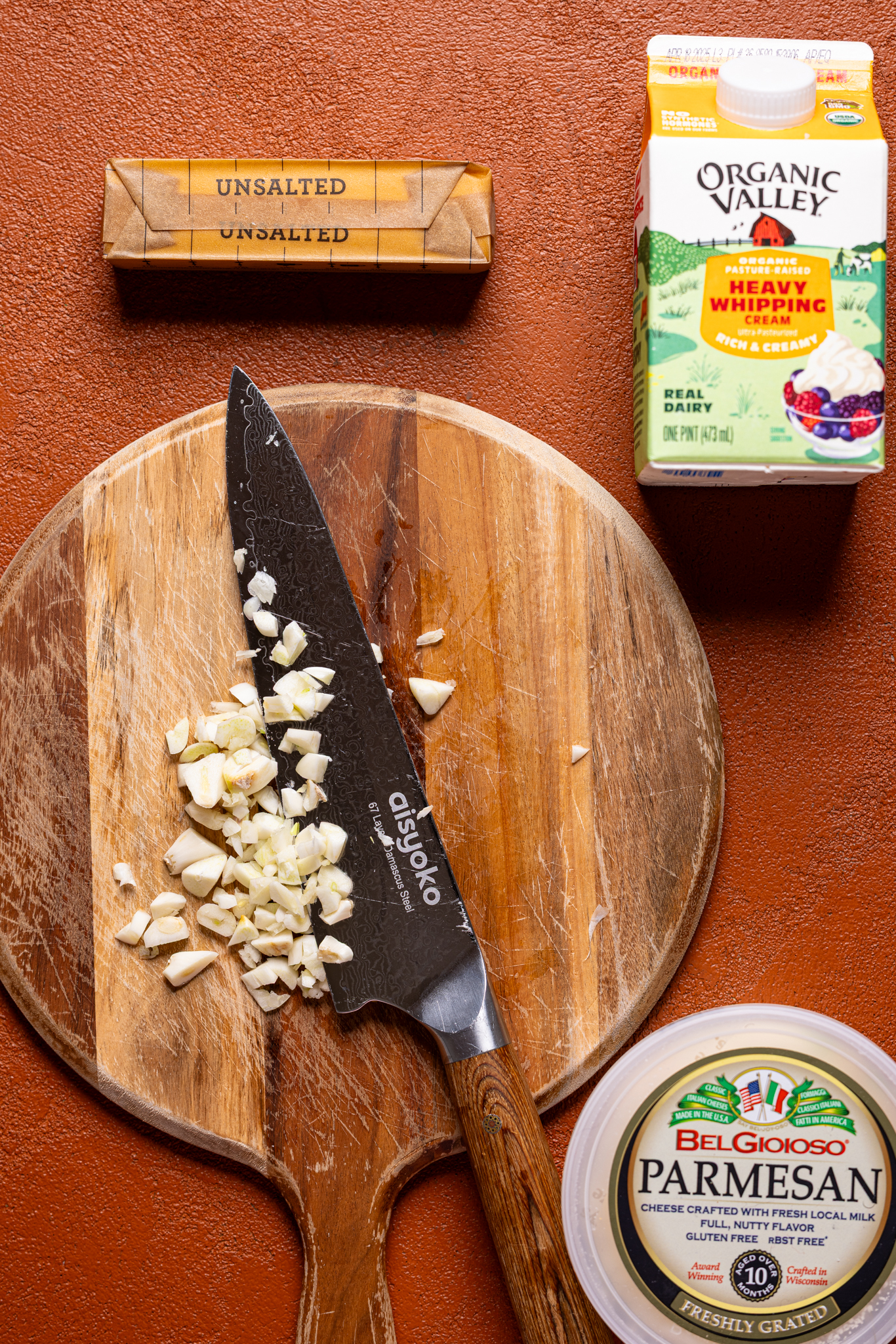 An image of ingredients on a cutting board and burnt orange table.